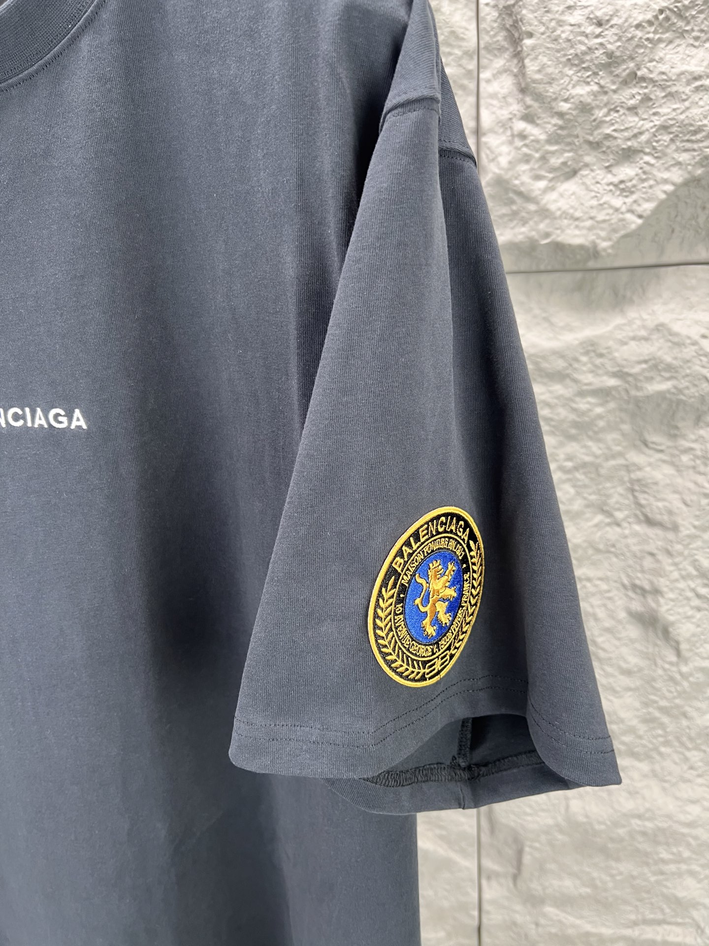 Vetements 胸前字母狮标徽章短袖280克精棉平纹面料 双纱拉架罗纹 平纹纯棉面料是一种高质量的棉纺织品 具有紧密的纺纱技术和高支数 这种面料具有柔软 舒适 透气和吸湿性好等特点 同时其纺织工艺要求也较高 纯棉质织物组织结构为平纹 面料的织物表面平整细腻 质地紧密 具有良好的吸湿透气性和舒适性 能够保持干爽舒适 由于其紧密的纺纱工艺 徽标刺绣章仔点缀 徽标采用进口定做绣线具有光泽感的丝光绣线进行定染 精细的细节处理 造就了立体微浮雕的刺绣效果 哑光挨针刺绣工艺是一种刺绣技术 颜色一致无色差 能与同款搭配营造 造型 驾驭各种场合 定制辅料 三标齐全