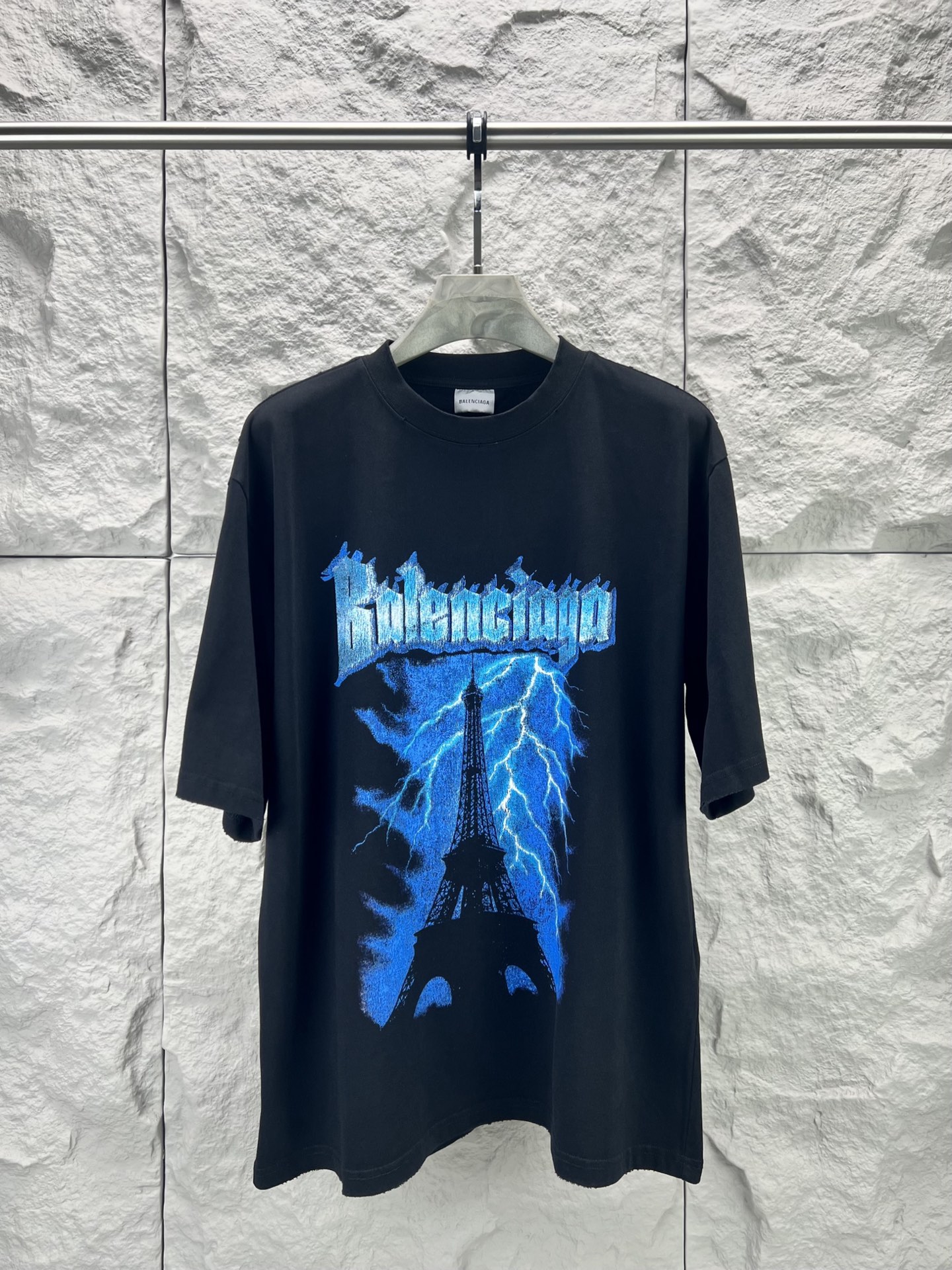 Balenciaga BALENCI*GA 铁塔闪电印花T恤 本品采用重磅精梳纯棉面料经预缩水处理 触感厚实挺括 宽松落肩版型贴合街头潮流风格 兼顾舒适与造型感 正面印花采用胶印结合做旧磨边工艺 先以高饱和度油墨还原蓝色闪电与埃菲尔铁塔轮廓