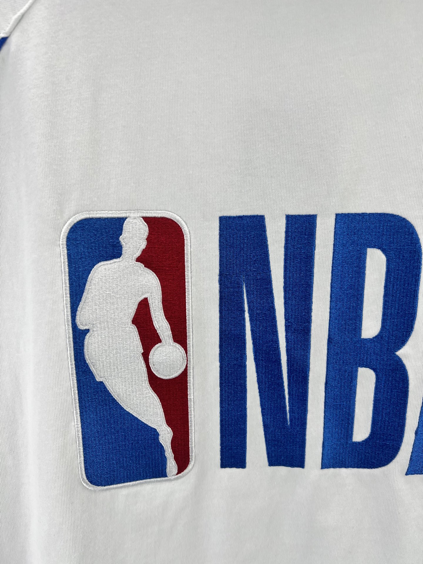 Balenciaga BALENCI*GA × NBA SS26联名T恤 采用科技网眼面料 经透气排汗工艺处理 兼具运动功能性与 廓形 衣身主体为黑色 肩部与袖口拼接撞色饰带 采用精密车缝工艺 线条利落 正面“BALENCIAGA”字样与数字“10”采用立体植绒或贴布绣工艺 边缘锁边牢固 不易脱线 领口为罗纹圆领 采用高弹氨纶混纺材质 久穿不易变形 下摆与袖口采用双针锁边工艺 提升整体耐用性 衣身印有NBA 标识 采用环保胶印工艺 图案清晰牢固 整体设计融合高端时装与运动元素 兼顾舒适穿着与视觉张力 适合潮流穿搭与收藏 整体走线平直细腻 面料舒适柔软 颜色一致无色差 能与同款搭配营造 造型 驾驭各种场合 定制辅料 三标齐全