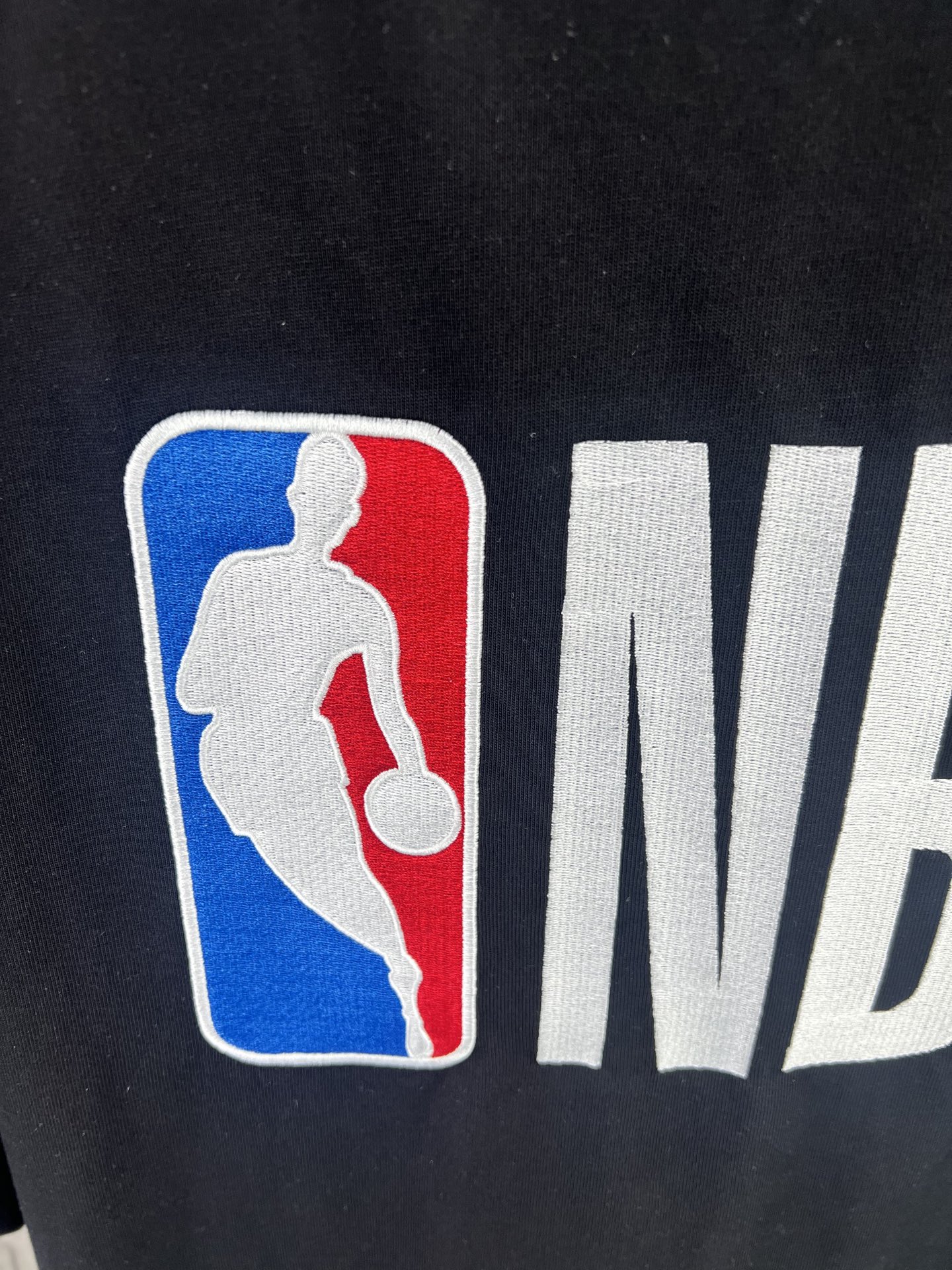 Balenciaga BALENCI*GA × NBA SS26联名T恤 采用科技网眼面料 经透气排汗工艺处理 兼具运动功能性与 廓形 衣身主体为黑色 肩部与袖口拼接撞色饰带 采用精密车缝工艺 线条利落 正面“BALENCIAGA”字样与数字“10”采用立体植绒或贴布绣工艺 边缘锁边牢固 不易脱线 领口为罗纹圆领 采用高弹氨纶混纺材质 久穿不易变形 下摆与袖口采用双针锁边工艺 提升整体耐用性 衣身印有NBA 标识 采用环保胶印工艺 图案清晰牢固 整体设计融合高端时装与运动元素 兼顾舒适穿着与视觉张力 适合潮流穿搭与收藏 整体走线平直细腻 面料舒适柔软 颜色一致无色差 能与同款搭配营造 造型 驾驭各种场合 定制辅料 三标齐全
