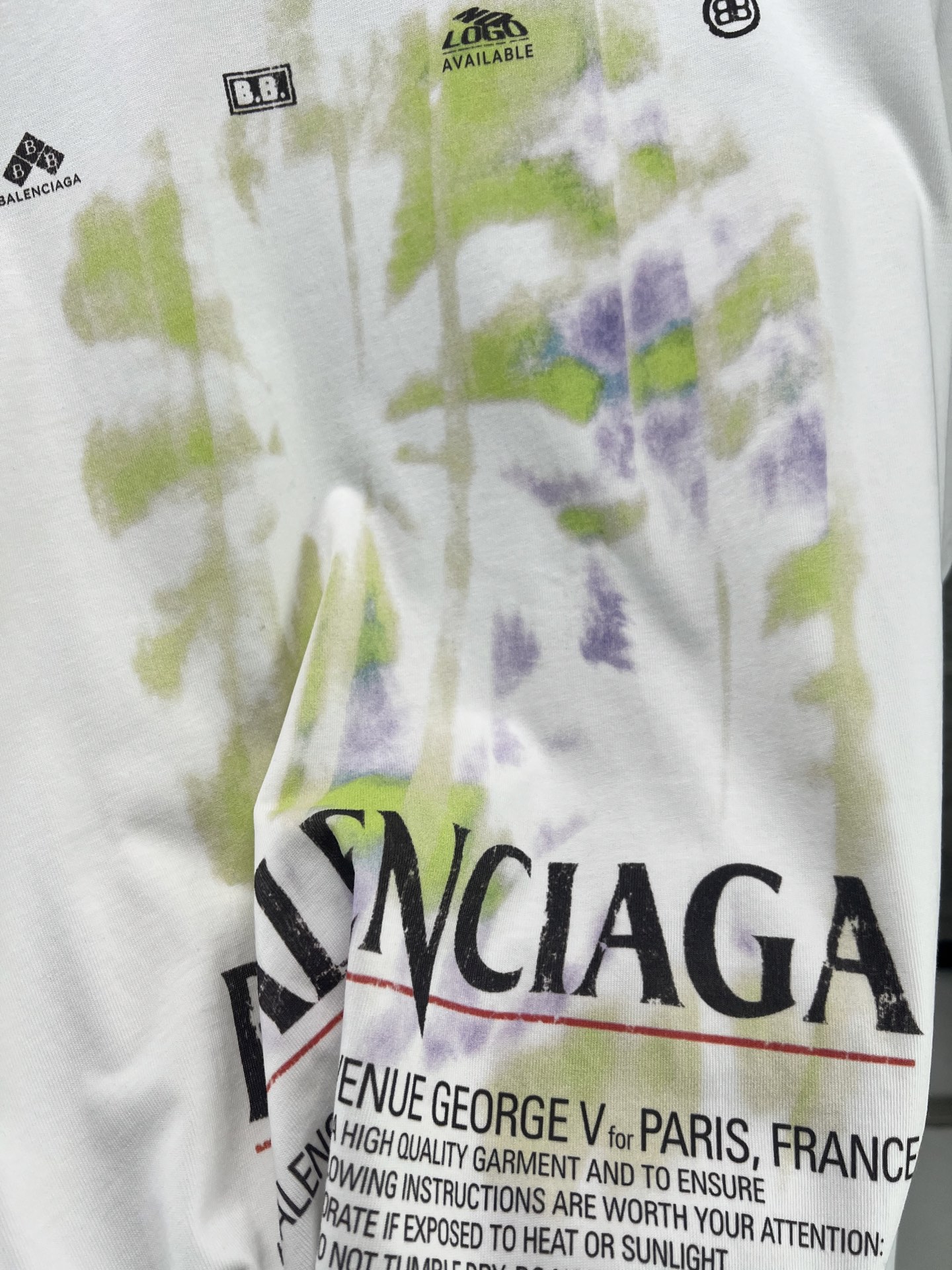 Balenciaga BALENCI*GA 椰树丛林圆领短袖 采用24支特纺紧密棉平纹面料 32支1×1罗纹 面料属于兼具挺括与舒适的中厚型针织 通过紧密纺技术使纤维排列平行 纱体紧致 毛羽显著减少 表面光洁平滑 面料仅经过高温定型机拉幅定形 兼具挺括性与柔软度 垂坠感适中 穿着有型不软塌 领型采用32支罗纹 属于中等偏轻的克重 触感更加柔软轻薄 与中版型的松弛感相呼应 采用渗透印花工艺搭配网点印花制作 渗透印花是一种使染料或浆料深入渗透至纤维内部的印花方式 通过特殊的助剂与压力控制 使色彩沉入面料而非浮于表面 由于采用渗透印花工艺 图案的视觉边界柔和 无胶质感 与白色底布的融合度更高 整体走线平直细腻 面料舒适柔软 颜色一致无色差 能与同款搭配营造 造型 驾驭各种场合 定制辅料 三标齐全