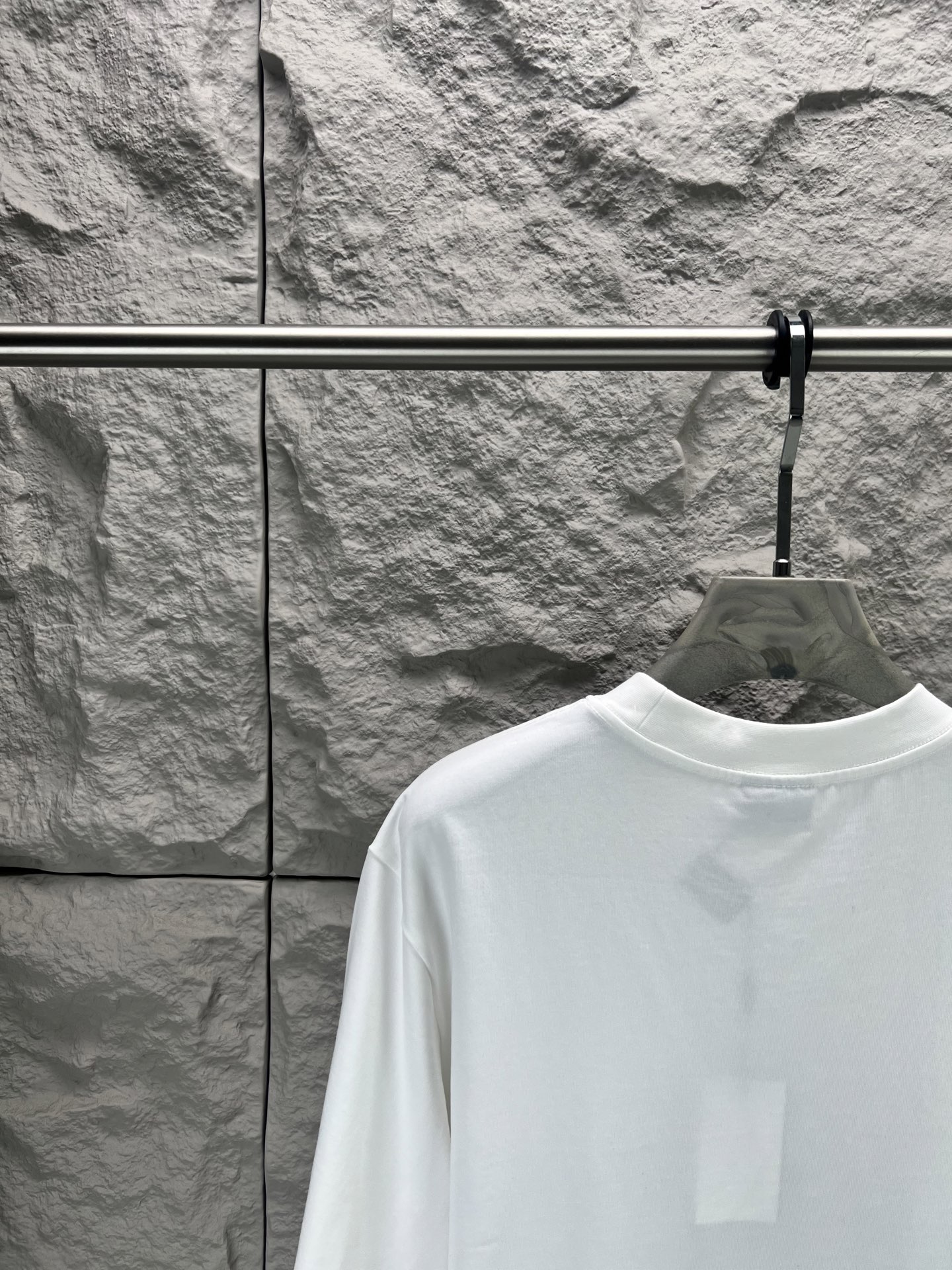 Balenciaga BALENCI*GA 椰树丛林圆领短袖 采用24支特纺紧密棉平纹面料 32支1×1罗纹 面料属于兼具挺括与舒适的中厚型针织 通过紧密纺技术使纤维排列平行 纱体紧致 毛羽显著减少 表面光洁平滑 面料仅经过高温定型机拉幅定形 兼具挺括性与柔软度 垂坠感适中 穿着有型不软塌 领型采用32支罗纹 属于中等偏轻的克重 触感更加柔软轻薄 与中版型的松弛感相呼应 采用渗透印花工艺搭配网点印花制作 渗透印花是一种使染料或浆料深入渗透至纤维内部的印花方式 通过特殊的助剂与压力控制 使色彩沉入面料而非浮于表面 由于采用渗透印花工艺 图案的视觉边界柔和 无胶质感 与白色底布的融合度更高 整体走线平直细腻 面料舒适柔软 颜色一致无色差 能与同款搭配营造 造型 驾驭各种场合 定制辅料 三标齐全