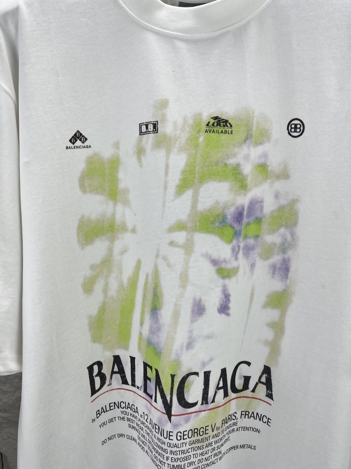 Balenciaga BALENCI*GA 椰树丛林圆领短袖 采用24支特纺紧密棉平纹面料 32支1×1罗纹 面料属于兼具挺括与舒适的中厚型针织 通过紧密纺技术使纤维排列平行 纱体紧致 毛羽显著减少 表面光洁平滑 面料仅经过高温定型机拉幅定形 兼具挺括性与柔软度 垂坠感适中 穿着有型不软塌 领型采用32支罗纹 属于中等偏轻的克重 触感更加柔软轻薄 与中版型的松弛感相呼应 采用渗透印花工艺搭配网点印花制作 渗透印花是一种使染料或浆料深入渗透至纤维内部的印花方式 通过特殊的助剂与压力控制 使色彩沉入面料而非浮于表面 由于采用渗透印花工艺 图案的视觉边界柔和 无胶质感 与白色底布的融合度更高 整体走线平直细腻 面料舒适柔软 颜色一致无色差 能与同款搭配营造 造型 驾驭各种场合 定制辅料 三标齐全