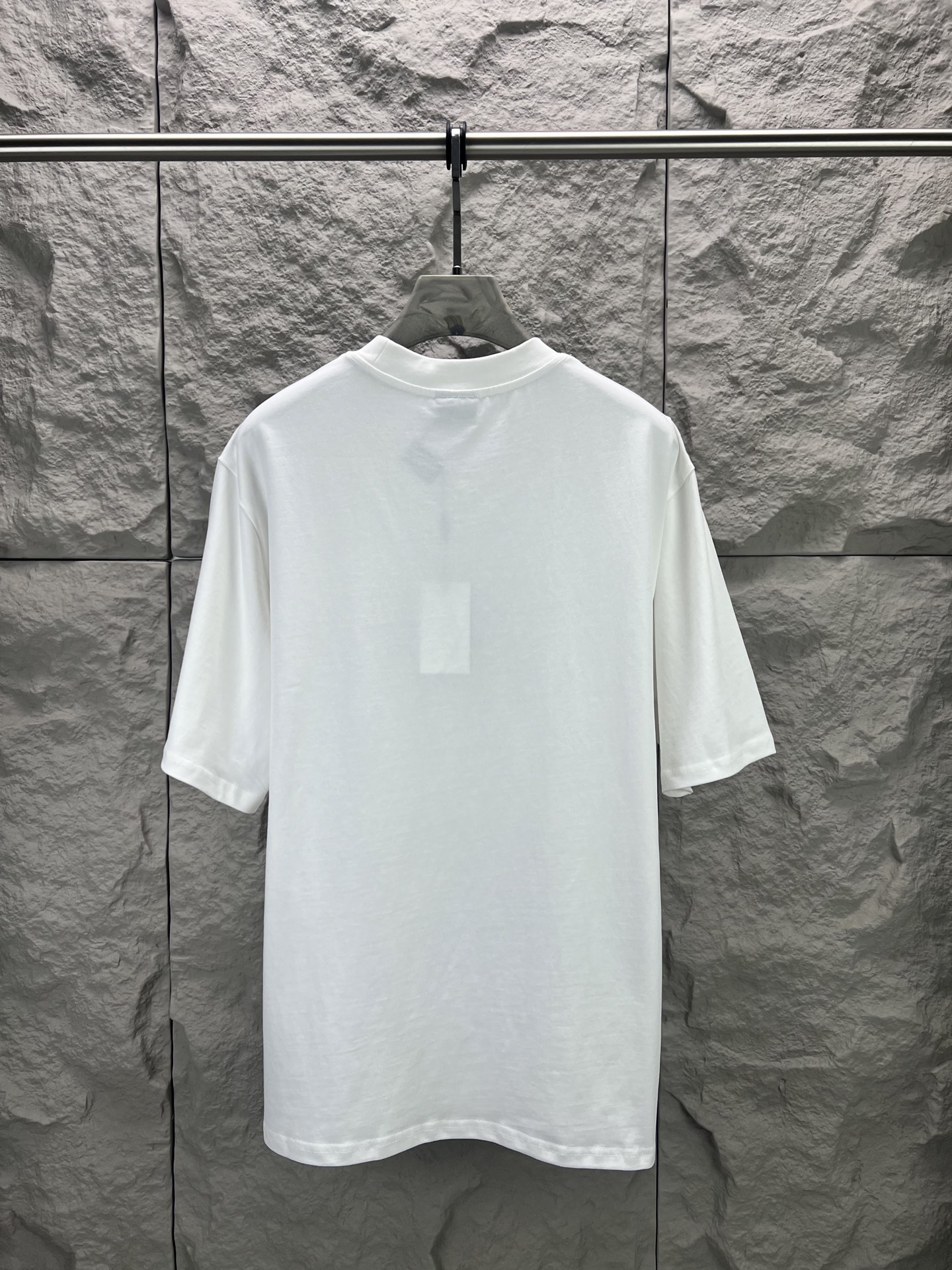 Balenciaga BALENCI*GA 椰树丛林圆领短袖 采用24支特纺紧密棉平纹面料 32支1×1罗纹 面料属于兼具挺括与舒适的中厚型针织 通过紧密纺技术使纤维排列平行 纱体紧致 毛羽显著减少 表面光洁平滑 面料仅经过高温定型机拉幅定形 兼具挺括性与柔软度 垂坠感适中 穿着有型不软塌 领型采用32支罗纹 属于中等偏轻的克重 触感更加柔软轻薄 与中版型的松弛感相呼应 采用渗透印花工艺搭配网点印花制作 渗透印花是一种使染料或浆料深入渗透至纤维内部的印花方式 通过特殊的助剂与压力控制 使色彩沉入面料而非浮于表面 由于采用渗透印花工艺 图案的视觉边界柔和 无胶质感 与白色底布的融合度更高 整体走线平直细腻 面料舒适柔软 颜色一致无色差 能与同款搭配营造 造型 驾驭各种场合 定制辅料 三标齐全