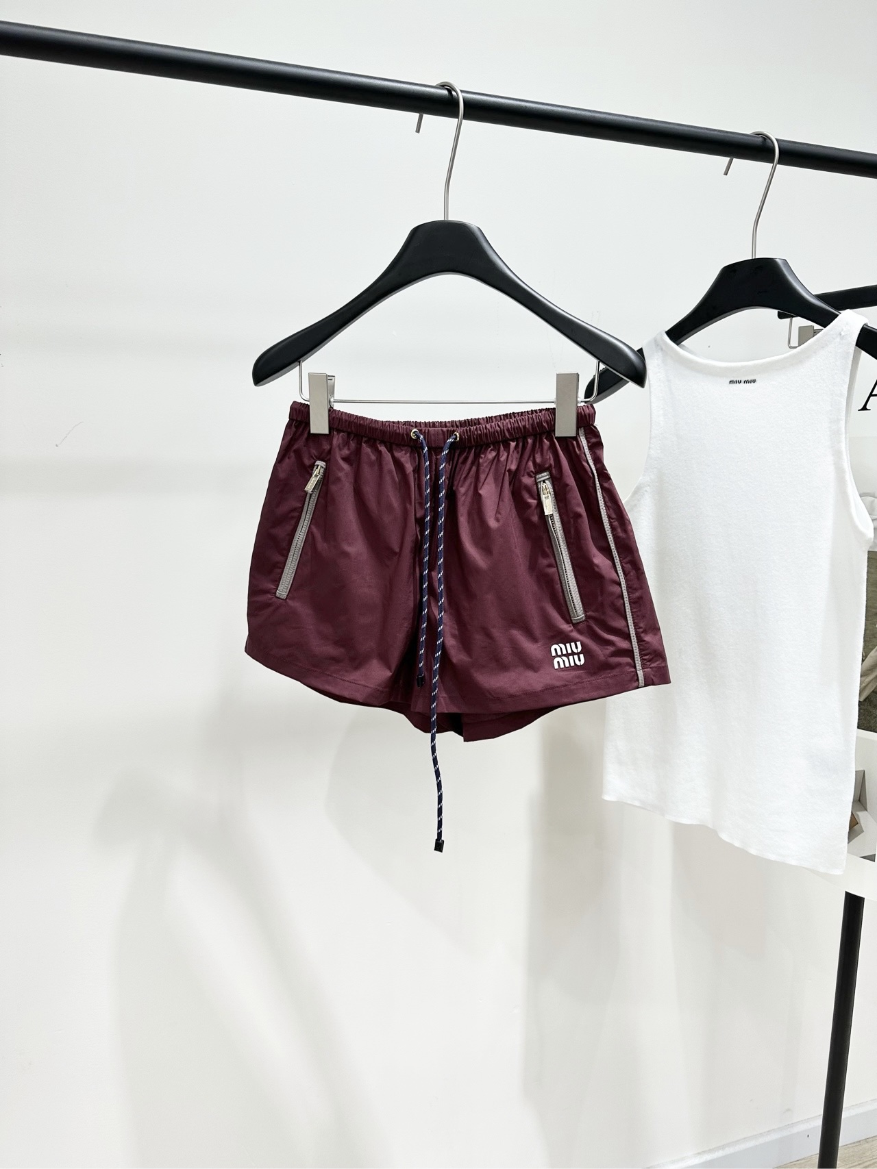 NO:733180,[M burgundy zipper drawstring casual shorts], made of nylon windproof fabric, color burgundy, these Miu* burgundy nylon shorts are a popular representative item of 'sweet and cool style'. Made of lightweight waterproof nylon fabric, with silver zipper pockets on both sides and a drawstring waistband. The lower left corner is embellished with the brand's iconic letter patch embroidery. The overall design has both a sporty and high-end feel. The burgundy color is white and eye-catching. Whether it is paired with basic styles or layered styles, it can easily create a fashionable focus.  Flat size S waist 64 elastic, hip 100, pants length 32 M waist 68 elastic, hip 104, pants length 33 L waist 72 elastic, hip 108, pants length 34 Manual measurement will have an error of 2 to 3cm, which is within the normal range,,miumiu,shorts,19860909【M酒红色拉链抽绳休闲短裤】 ,面料尼龙防风面料 颜色酒红色 这款Miu*酒红色尼龙短裤 是备受追捧的“甜酷风”代表单品 采用轻盈防水尼龙面料 搭配两侧银色拉链口袋和抽绳腰头 左下角点缀品牌标志性字母贴布刺绣 整体设计兼具运动感与高级感 酒红色调显白又吸睛 无论是搭配基础款还是叠穿造型 都能轻松打造时髦焦点 平铺尺码 S腰围64弹力,臀围100,裤长32 M腰围68弹力,臀围104,裤长33 L腰围72弹力,臀围108,裤长34 手工测量会有2～3cm误差属于正常范围,,miumiu,shorts,,Women's clothing