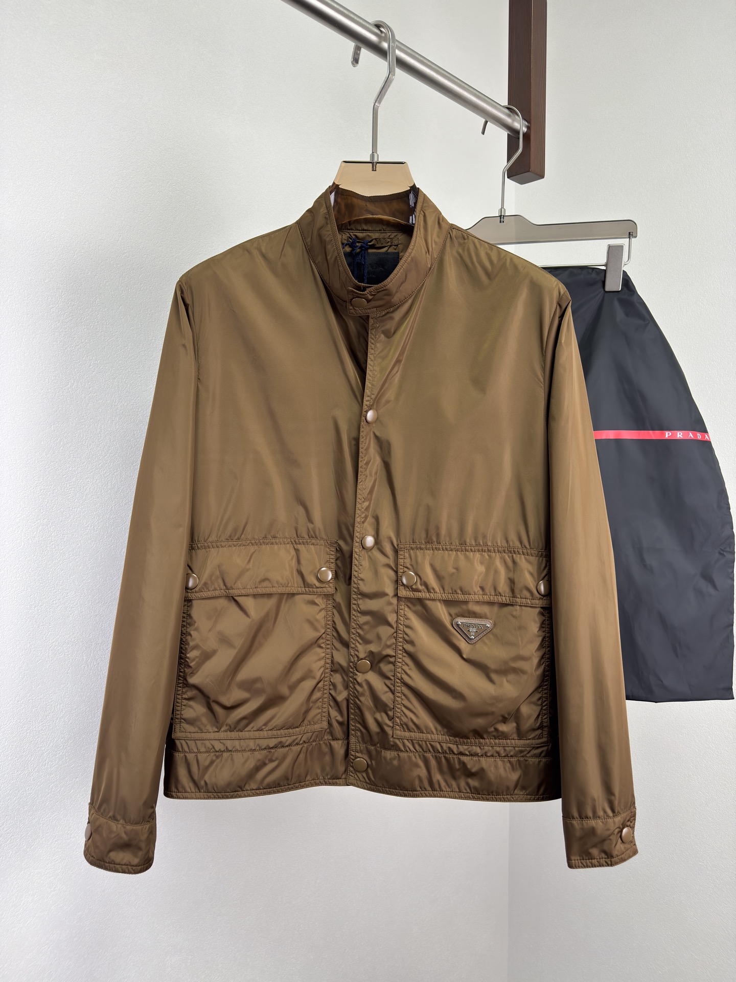 NO:515240,PRADA's new 25-Autumn and Winter stand-collar multi-pocket jacket is reshapes the classic tooling outline with Re-Nylon material, combining practical details and simple lines to create a pioneering masterpiece that combines functionality and aesthetics. It uses the brand's iconic Re-Nylon material to be light and durable, windproof and waterproof. It has a neat tooling silhouette, and a balanced function and aesthetics. The regular version stand-collar neatly cut out the neck lines, and matches it with a straight bottom edge to create a straight figure. The large-capacity workwear air pocket is practical at the waist, the flip design is matched with snap buckle opening and closing, and the waist zipper pocket opening and closing.  Precision details, showing the ingenuity of straight sleeves and cuff straps + snap buttons neatly matched with adjustable straps and snap buttons, flexible convergence, the same color as the same fabric, the subtleties of snap buttons are exquisite, the brand's iconic logo is inlaid with enamel craftsmanship. The craftsmanship is exquisite, the inner and outer lining is the same as the outer body, and the material continues the environmental protection gene of Re-Nylon. The lining is made of the same material, showing PRADA's ultimate pursuit of quality. The zipper details of the zipper are presented with metal texture, and the brand letters are precisely engraved. Each opening and closing is an exclusive ceremony, and the brand DNA is hidden in the details. Color black Cinnamon Size M-3XL (48-56),,prada,prada,jackets & coats,alexander wang19860909PRADA普拉达 25秋冬新品立领多口袋夹克,以Re-Nylon材质重塑经典工装轮廓,融合实用细节与简洁线条,打造一件兼具功能性与美学的先锋杰作. 采用品牌标志性Re-Nylon材质轻盈耐用,防风防水.利落工装廓形,功能与美学平衡.常规版型立领利落剪裁勾勒颈部线条,搭配平直底边,塑造挺拔身姿.大容量工装风口袋腰间实用口袋,翻盖设计搭配按扣开合,腰侧拉链口袋开合. 精密细节,彰显匠心直筒袖与袖口袢带+按扣利落袖型搭配可调节袢带与按扣,灵活收束,同面料颜色一致按扣细微之处见考究,涂珐琅三角形金属徽标品牌标志性徽标以珐琅工艺镶嵌. 工艺精琢,内外如一内衬与外身一致材质延续Re-Nylon的环保基因,内衬采用相同材质,展现PRADA对品质的极致追求.攥刻PRADA字母标识拉链片拉链细节以金属质感呈现,品牌字母标识精密雕刻,每一次开合皆是专属仪式,细节中藏匿品牌DNA. 颜色黑色 肉桂色 尺码M-3XL（48-56）,,prada,prada,jackets & coats,alexander wang,Men's clothing