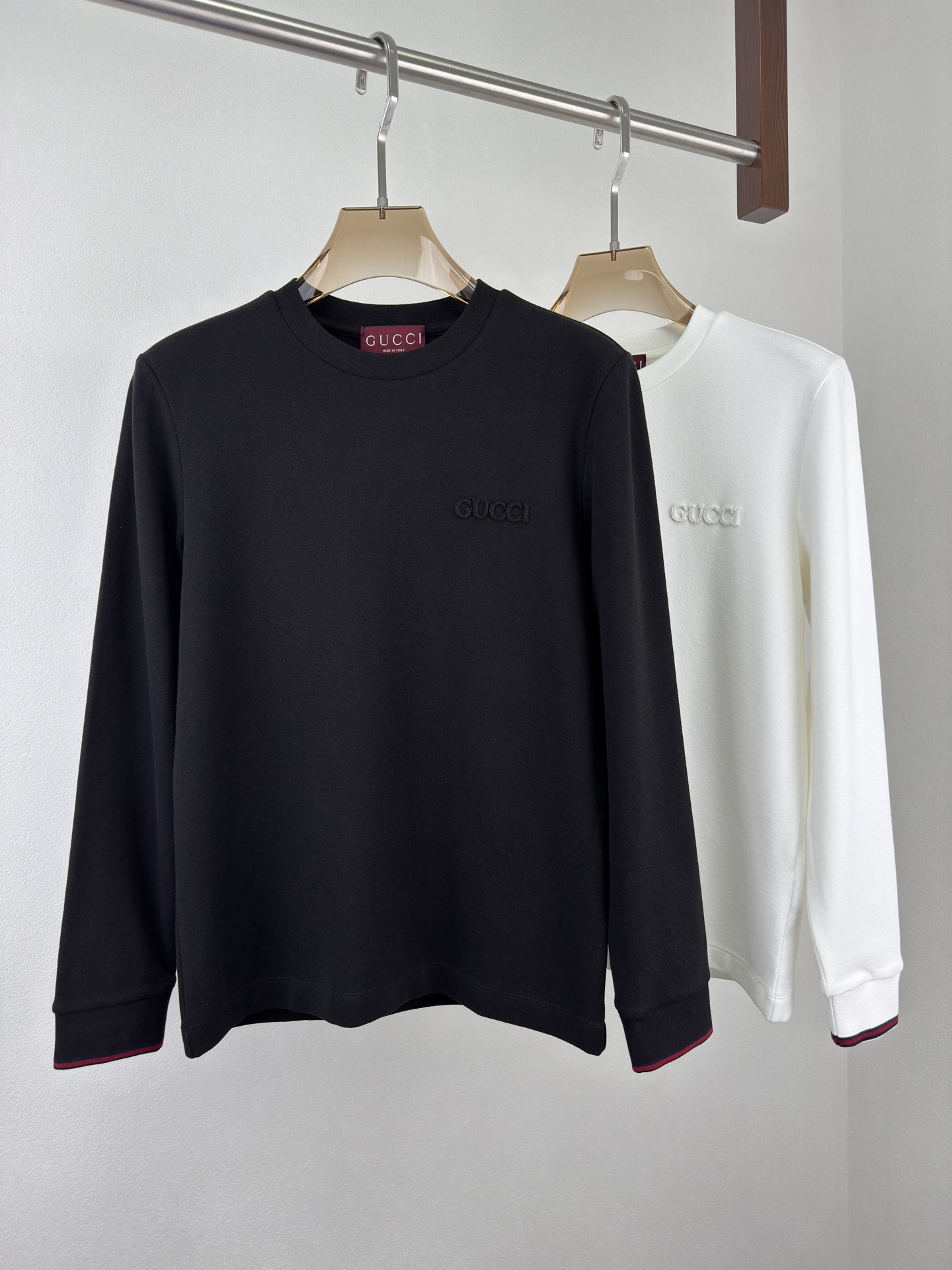 NO:515290,GUCCI 25 Autumn and Winter Thin Velvet Lapel Base Shirt. This three-color ribbed webbing base shirt turns the elegance of the tennis court, the legend of the brand, and the contemporary street style into a wearable declaration. The classic three-color striped webbing piping cuffs and the 'Gucci' embroidery on the chest complement each other. The cuffs on both sides are matched with classic color stripes to replicate the classic design of the tennis era. The blue, red and blue three-color Solona ribbed cuffs are like a dazzling symbol, with high elasticity and ductility allowing movement to be free, and the details show the brand's persistence in sports aesthetics. Details are attitudes, and classic elements are new.  Gucci's 'pattern embroidery brand's iconic letters are embedded in the body in a three-dimensional fabric embroidery with low-key embroidery, quietly blooming in a simple design. The fashion attitude does not need to be ostentatious, low-key but does not lose its presence. It is a double declaration of fashion and quality. The velvet cotton feels comfortable material, with a perfect balance of breathability and softness, and the surface honeycomb texture adds a sense of layering. Wearing it, comfort and style never conflict. Color black white Size M-3XL (48-56 sizes), gucci, alexander wang19860909GUCCI 25秋冬薄绒翻领打底衫.这件三色罗纹织带打底衫,是把网球场的优雅、品牌的传奇、当代的街头风,都化作一件可穿的宣言. 经典三配色条纹织带滚边袖口与胸前'Gucci'字样贴布刺绣交相辉映. 两侧袖口搭配经典配色条纹复刻网球时代的经典设计,蓝红蓝三色索罗娜罗纹袖口如一道亮眼的符号,高弹延展性让活动自如,细节处尽显品牌对运动美学的执着,细节即态度,经典元素玩出新意. Gucci'贴布刺绣品牌标志性字母以顺面料颜色立体贴布刺绣低调嵌入衣身,在简约设计中悄然绽放,时尚态度无需张扬,低调却不失存在感,是时尚与品质的双重宣言. 薄绒棉感舒适材质,透气性与柔软度完美平衡,表面蜂窝纹理增添层次感,穿着它,舒适与格调从不冲突 颜色黑色 白色 尺码 M-3XL（48-56码）,,gucci,alexander wang,Men's clothing