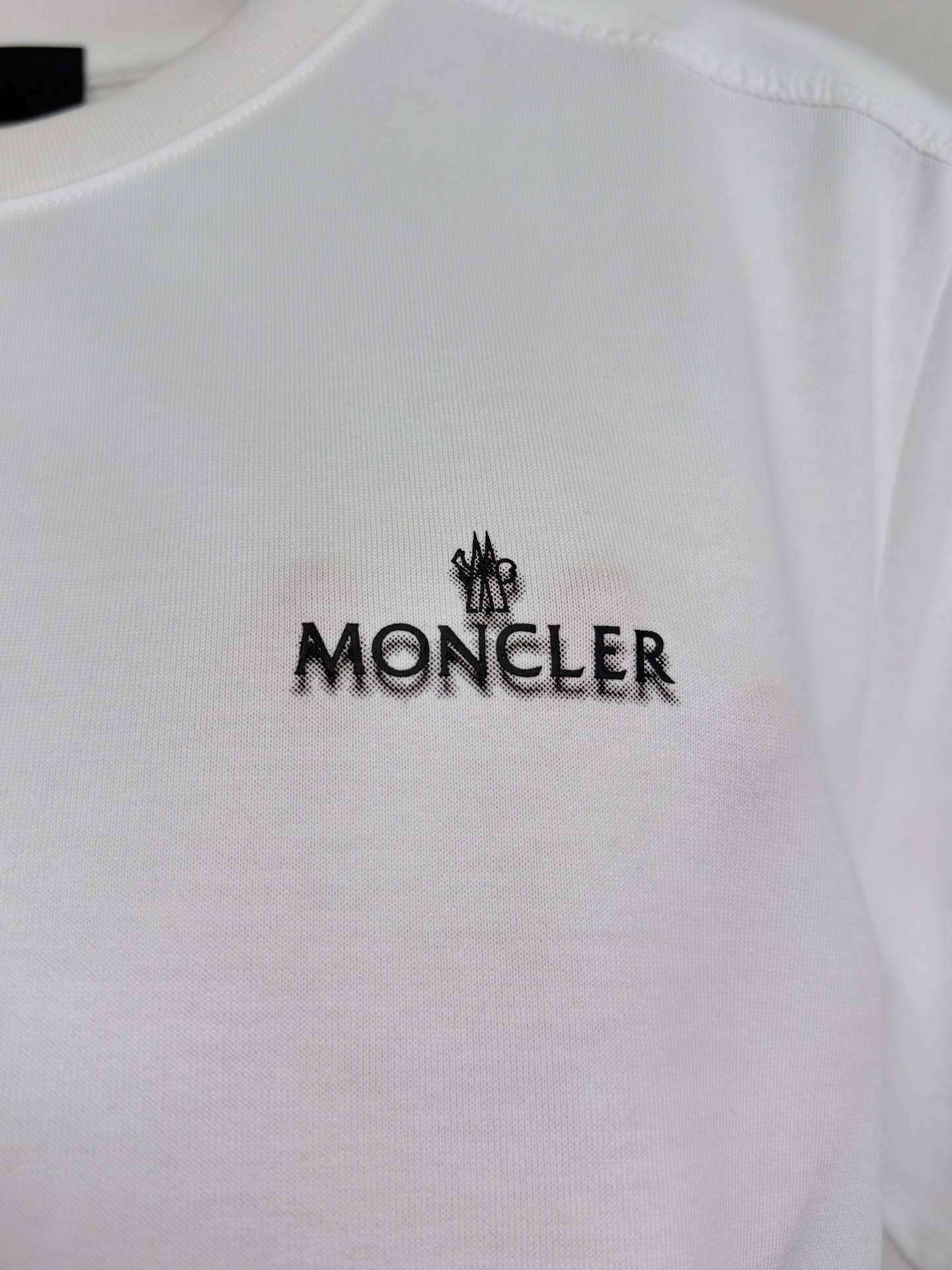 MONCLER 26春夏 黑标系列，这款T恤是品牌DNA的现代创新宣言——将经典的户外黑标系列标志大胆重