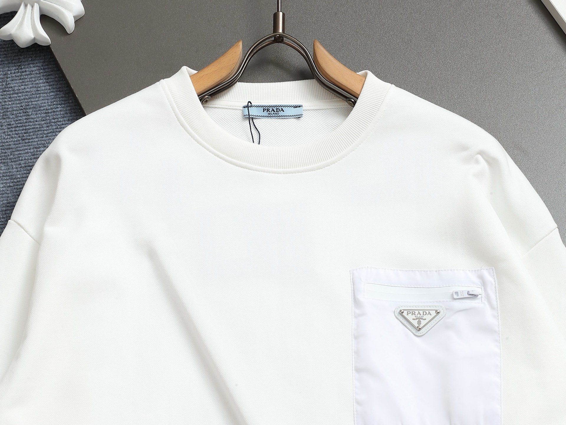        PRAD*微宽版型
普拉达/25ss新款胸前三角标口袋款圆领卫衣，这款卫衣融运动风极简主义