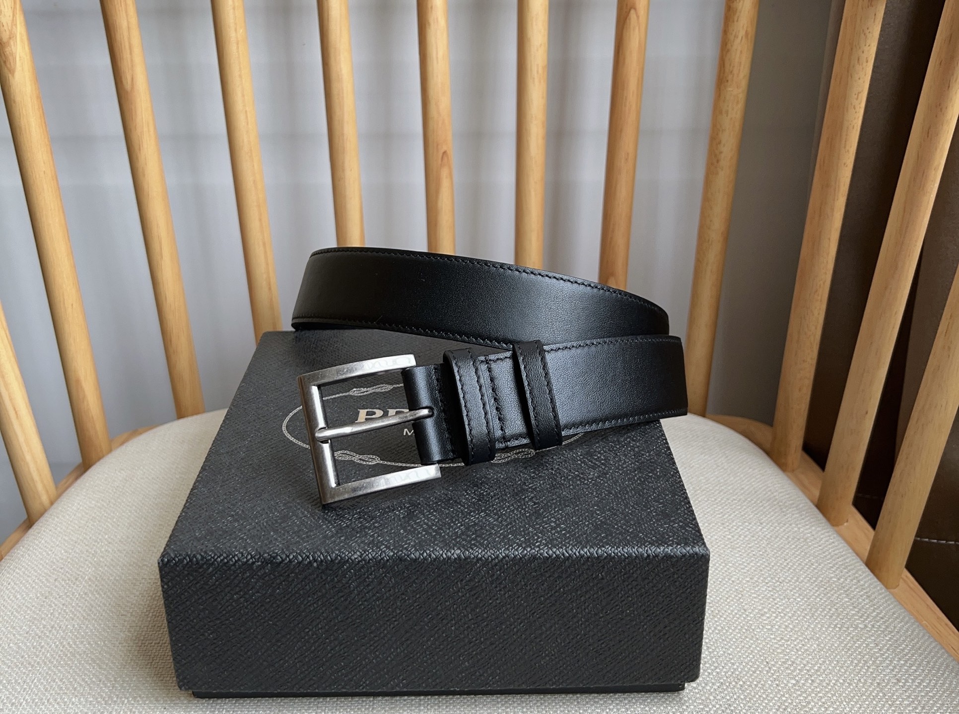 Ceinture Prada en cuir noir avec boucle argentée et logo iconique