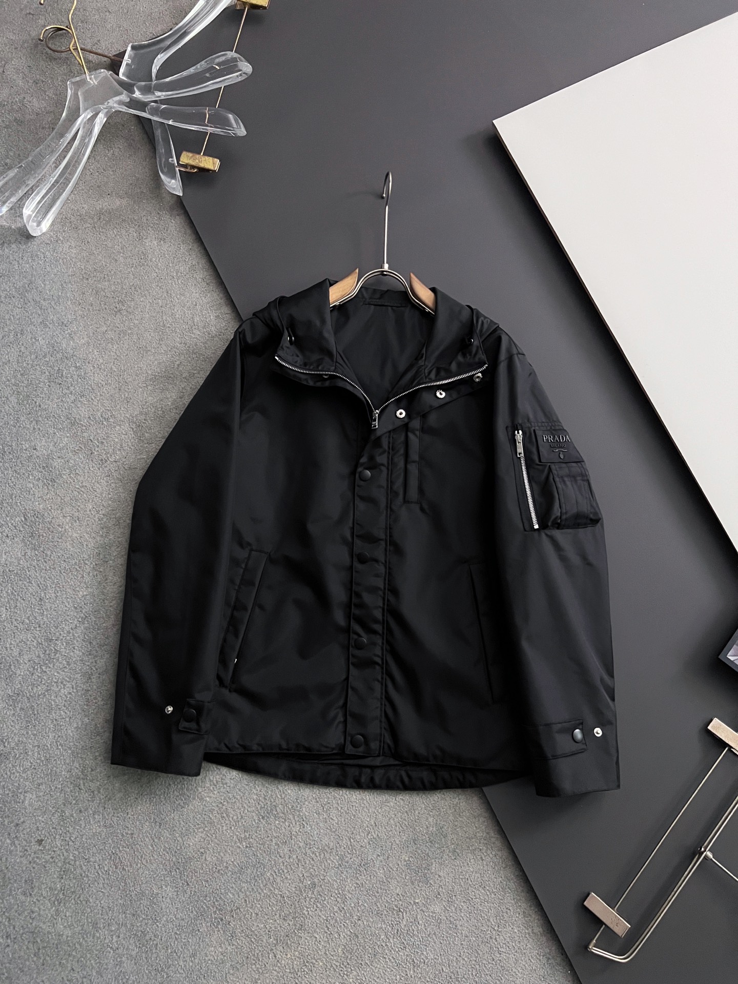 NO:509688,) Prad*2025 early autumn men's high-end fashion hooded outdoor jacket jacket, new 25 spring and summer style, official counter main display, Hong Kong foreign business channels, outdoor must-have items, exclusively for sale. On the basis of minimalism, it produces extraordinary creativity, and uses clever design techniques to innovate elsewhere. The front design is broken and contradictory cloth, forming a strong hedge, and the visual effect is unique. The chest decoration is printed with a brand LOGO, which is simple and atmospheric, demonstrating the brand's identity. The sleeves are equipped with the brand's exclusive design, which echoes the front chest printing, which is both sporty and fashionable!  It has a distinct recognition, showing the vitality of the city, and is highly shaped and practical!  The fabric is made of Japanese Toray company customized fabric (a first-line luxury clothing royal fabric manufacturer) with waterproof and windproof characteristics, both comfort and breathability, the upper body is light and burden-free, the hooded design has a strong sense of detail and quality. All auxiliary materials are supplied by customers and all auxiliary materials are engraved with brand LOGO, which is very expensive, luxurious and high-end!  The details show the ingenious craftsmanship, the auxiliary materials are all supplied to customers, and the workmanship is extremely rigorous and sophisticated. The outline structure of the whole body continues the basic form of the M family, expressing the simple and atmospheric characteristics in place, with a full upper body shape, which can easily control various body shapes, and the outfit meets the needs of the transition season!  Size 48-56, prada, jackets & coats, jackets & coats, hats, alexander wang19860909）Prad*2025早秋男士高端时装款连帽户外夹克外套,25年春夏新款,官方专柜主推展示,香港洋行渠道,户外必选单品,独家出售. 在极简的基础上洐生出非凡的创意,用巧妙的设计手法进行别处一格的创新,前幅设计破缝拼接撞色布,形成强烈的对冲,设觉效果别具一格,胸前饰印有品牌LOGO,简单大气,彰显品牌身份地位. 袖子搭载品牌专属章仔设计,与前胸印花形成呼应,即运动又时尚！辨识度鲜明,尽显都市活力色彩,且塑造性和实穿性极高！ 面料选用日本东丽公司订制面料（一线奢侈品成衣御用面料商）具备防水防风特性,舒适性与透气性兼备,上身轻便且无负担感,连帽的设计,整体细节品质感超强,辅料全系客供,全客供辅料,都刻有品牌LOGO, 非常贵奢高级！ 细节之处尽显匠心工艺,辅料皆为客供,做工极为严谨考究,通体的轮廓构造延续了M家族基础形态,将简约大气的特征表现到位,上身型款十足,轻松驾驭各种身型,穿搭符合过渡季的需求！尺码48-56,,prada,jackets & coats,jackets & coats,hats,alexander wang,Men's clothing