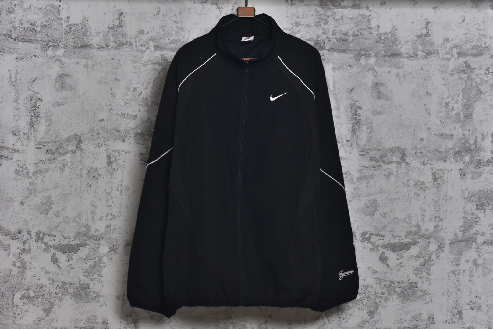 #Supreme 25ss 联名Swoosh图案立领夹克外套 三色全部购入原版开发，面料定织定染，25年春夏第4周，与Nike的联名系列中，此款运动夹克设计上融合了双方品牌的经典元素，同时注重材质与细节的质感，采用抗水涤纶面料，版型是宽松剪裁设计，背后印有大号Swoosh图案，3M反光细节提升夜间能见度，Supreme Logo以低调形式呈现（如袖口，口袋处），符合近年“克制设计”趋势，适合日常搭配，多色可选，复古与未来感并存，辅料全线独立开发，男女同款 尺码：M-XXL-选品中心