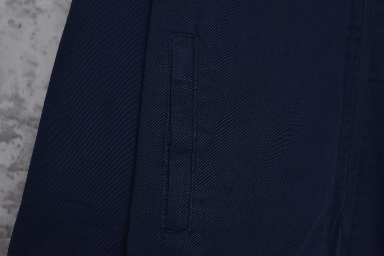 图片[5]-#Miu Miu 25Fw Miu小标法工夹棉外套 采用16OZ进口高克重牛仔面料，选用更长绒的优质棉花纺成高捻度的特规纱线，以确保最终面料的强度与最终染色的纯净度。经典的牛仔斜纹织法被精确校准，以在达成高密度的同时，保留恰到好处的柔软潜力，避免过于板硬。经纬纱的排列密度远超普通牛仔，从而获得极高的抗撕裂强度和耐磨性。定染对版色纺法工蓝，染色工程师需要反复调试靛蓝的配方，精确控制染色温度、时长和氧化次数，通过多层重复染色来模拟出时间赋予的色彩层次感。内里填充400D洗水棉，填充物为经过预洗处理的棉絮。“预洗水”工艺至关重要，它去除了棉絮的“新”感和僵硬感，使其从一开始就呈现出柔软、蓬松且略带旧化肌理的触感，确保外套穿着时立即舒适，且外观呈现出自然的蓬松感和慵懒的廓形。领部材质选用特规灯芯绒，其绒条宽度和棉绒品质均为定制，以匹配主面料的厚重质感与复古风格。胸前贴布绣花首先将设计好的图案以定制裁片的形式制作出来，再以精密缝纫的方式固定在胸前主体上。这款法工外套，是一件融合了传统工装基因与高级时装工艺的复杂作品。从独家定织定染的面料，到创新性的400D洗水棉填充结构，再到耗时费工的拼接领部与立体贴布绣花，每一个环节都设置了极高的技术和成本门槛。它不仅仅是一件外套，更是一件体现了品牌对材料学、工艺学和美学极致追求的“可穿戴艺术品”。 尺码：38 40 42-选品中心