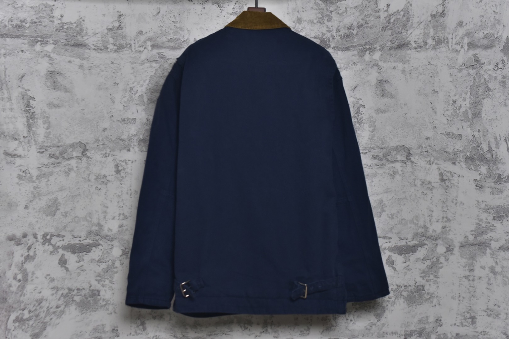 图片[2]-#Miu Miu 25Fw Miu小标法工夹棉外套 采用16OZ进口高克重牛仔面料，选用更长绒的优质棉花纺成高捻度的特规纱线，以确保最终面料的强度与最终染色的纯净度。经典的牛仔斜纹织法被精确校准，以在达成高密度的同时，保留恰到好处的柔软潜力，避免过于板硬。经纬纱的排列密度远超普通牛仔，从而获得极高的抗撕裂强度和耐磨性。定染对版色纺法工蓝，染色工程师需要反复调试靛蓝的配方，精确控制染色温度、时长和氧化次数，通过多层重复染色来模拟出时间赋予的色彩层次感。内里填充400D洗水棉，填充物为经过预洗处理的棉絮。“预洗水”工艺至关重要，它去除了棉絮的“新”感和僵硬感，使其从一开始就呈现出柔软、蓬松且略带旧化肌理的触感，确保外套穿着时立即舒适，且外观呈现出自然的蓬松感和慵懒的廓形。领部材质选用特规灯芯绒，其绒条宽度和棉绒品质均为定制，以匹配主面料的厚重质感与复古风格。胸前贴布绣花首先将设计好的图案以定制裁片的形式制作出来，再以精密缝纫的方式固定在胸前主体上。这款法工外套，是一件融合了传统工装基因与高级时装工艺的复杂作品。从独家定织定染的面料，到创新性的400D洗水棉填充结构，再到耗时费工的拼接领部与立体贴布绣花，每一个环节都设置了极高的技术和成本门槛。它不仅仅是一件外套，更是一件体现了品牌对材料学、工艺学和美学极致追求的“可穿戴艺术品”。 尺码：38 40 42-选品中心