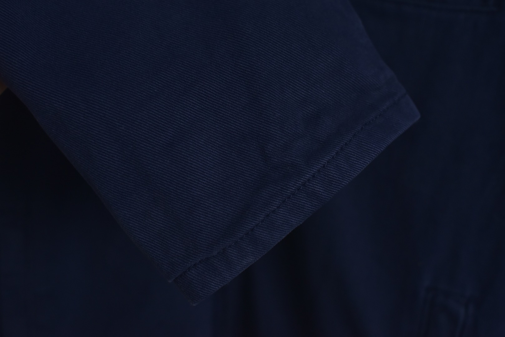 图片[8]-#Miu Miu 25Fw Miu小标法工夹棉外套 采用16OZ进口高克重牛仔面料，选用更长绒的优质棉花纺成高捻度的特规纱线，以确保最终面料的强度与最终染色的纯净度。经典的牛仔斜纹织法被精确校准，以在达成高密度的同时，保留恰到好处的柔软潜力，避免过于板硬。经纬纱的排列密度远超普通牛仔，从而获得极高的抗撕裂强度和耐磨性。定染对版色纺法工蓝，染色工程师需要反复调试靛蓝的配方，精确控制染色温度、时长和氧化次数，通过多层重复染色来模拟出时间赋予的色彩层次感。内里填充400D洗水棉，填充物为经过预洗处理的棉絮。“预洗水”工艺至关重要，它去除了棉絮的“新”感和僵硬感，使其从一开始就呈现出柔软、蓬松且略带旧化肌理的触感，确保外套穿着时立即舒适，且外观呈现出自然的蓬松感和慵懒的廓形。领部材质选用特规灯芯绒，其绒条宽度和棉绒品质均为定制，以匹配主面料的厚重质感与复古风格。胸前贴布绣花首先将设计好的图案以定制裁片的形式制作出来，再以精密缝纫的方式固定在胸前主体上。这款法工外套，是一件融合了传统工装基因与高级时装工艺的复杂作品。从独家定织定染的面料，到创新性的400D洗水棉填充结构，再到耗时费工的拼接领部与立体贴布绣花，每一个环节都设置了极高的技术和成本门槛。它不仅仅是一件外套，更是一件体现了品牌对材料学、工艺学和美学极致追求的“可穿戴艺术品”。 尺码：38 40 42-选品中心