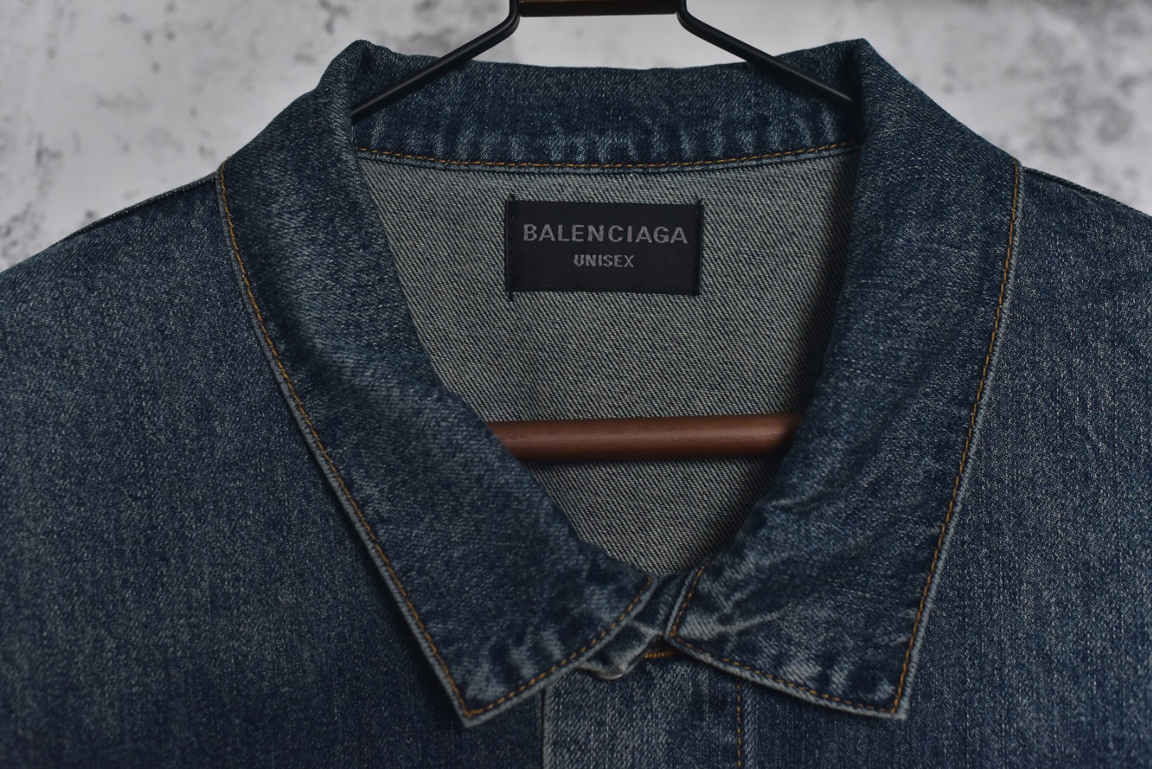 图片[6]-#Balenciaga/巴黎世家 25Fw 银胶带印花蓝牛仔外套 定制赛络纺工艺牛仔面料。此工艺使两根粗纱在纺纱阶段保持一定间距，经牵伸后由前罗拉输出，再汇合加捻成一根单纱。 赛络纺技术使最终织造出的丹宁面料具有卓越的强度、优异的耐磨性以及独特的柔软手感。纱线结构紧密，面料纹理清晰、光泽柔和，布面毛羽显著减少，呈现出普通牛仔无法比拟的细腻、挺括且高质感的视觉和触觉体验，为后续的重工艺处理提供了完美的基础。所有接缝、拼接处均采用高张力、高密度、均匀一致的针距进行缝制。线迹精准如机械制图，无任何跳针、断线或线头。内侧包边处理工整，承受高强度穿着与洗涤后仍能保持结构稳定，体现了世界级大厂对生产流程的严苛品控和无可挑剔的缝制技术。印花工艺复杂性： 这是整件外套最具技术挑战性的部分，其“胶带”效果并非普通印花或贴膜，而是采用了极为繁琐的多层厚板胶浆印花与特种闪粉混合印刷技术。厚板印刷： 通过多次重复印刷特调高分子胶浆，在面料表面堆叠出具有显著3D立体浮雕感的“胶带”条纹。每一次印刷都需经过精确对位和高温烘干定型，确保图案边缘锐利如刀刻，厚度均匀一致，手感坚硬且极具冲击力。闪粉融合： 在胶浆未完全固化前，将定制的高折射率微闪片通过精密筛网均匀撒在印花表面，并使其牢固嵌入胶浆内部。此步骤需精确控制胶浆粘度和闪粉的附着力，确保闪粉分布均匀、牢固不脱落，且光泽璀璨持久。 品质体现： 最终形成的印花图案不仅具有强烈的视觉立体感和触摸感，更因其高强度的物化特性，实现了极高的耐撕裂性、抗皱性和耐洗牢度。印花部分不会开裂、剥落或变黄，闪粉在日常穿着中也能最大限度地保持其闪耀效果，经久如新。这种工艺将装饰性与功能性推向了极致，成本高昂，良品率极低，是大厂才能驾驭的复杂技术 尺码：1 2 3-选品中心