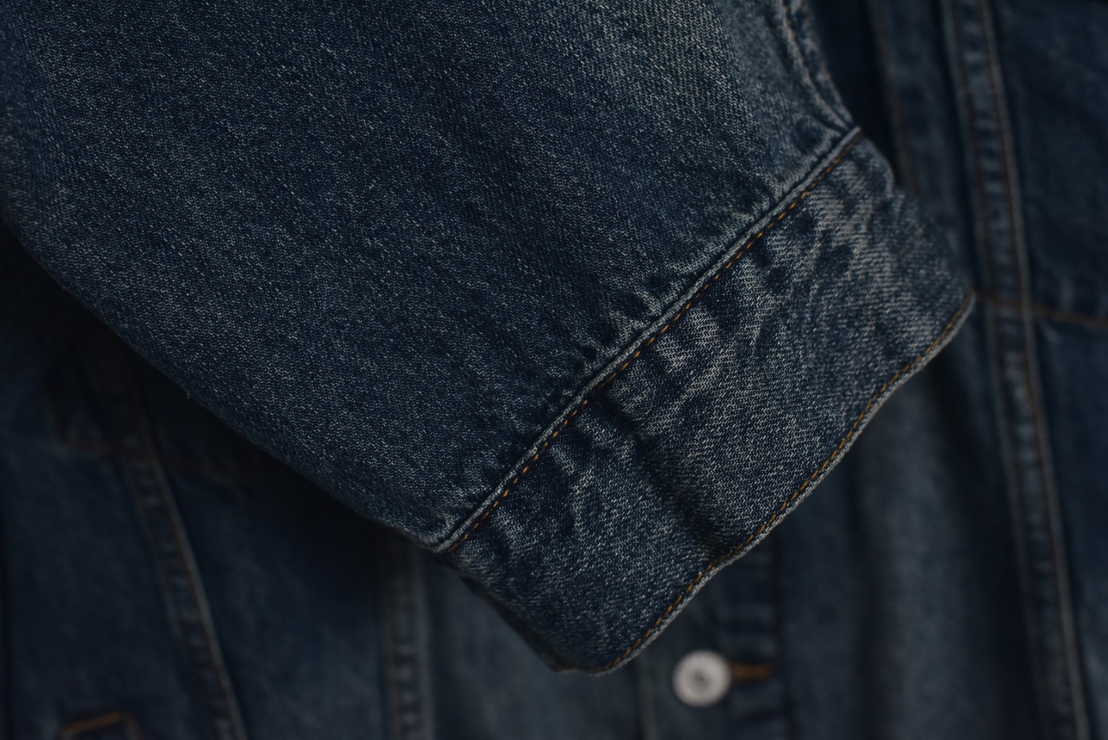 图片[8]-#Balenciaga/巴黎世家 25Fw 银胶带印花蓝牛仔外套 定制赛络纺工艺牛仔面料。此工艺使两根粗纱在纺纱阶段保持一定间距，经牵伸后由前罗拉输出，再汇合加捻成一根单纱。 赛络纺技术使最终织造出的丹宁面料具有卓越的强度、优异的耐磨性以及独特的柔软手感。纱线结构紧密，面料纹理清晰、光泽柔和，布面毛羽显著减少，呈现出普通牛仔无法比拟的细腻、挺括且高质感的视觉和触觉体验，为后续的重工艺处理提供了完美的基础。所有接缝、拼接处均采用高张力、高密度、均匀一致的针距进行缝制。线迹精准如机械制图，无任何跳针、断线或线头。内侧包边处理工整，承受高强度穿着与洗涤后仍能保持结构稳定，体现了世界级大厂对生产流程的严苛品控和无可挑剔的缝制技术。印花工艺复杂性： 这是整件外套最具技术挑战性的部分，其“胶带”效果并非普通印花或贴膜，而是采用了极为繁琐的多层厚板胶浆印花与特种闪粉混合印刷技术。厚板印刷： 通过多次重复印刷特调高分子胶浆，在面料表面堆叠出具有显著3D立体浮雕感的“胶带”条纹。每一次印刷都需经过精确对位和高温烘干定型，确保图案边缘锐利如刀刻，厚度均匀一致，手感坚硬且极具冲击力。闪粉融合： 在胶浆未完全固化前，将定制的高折射率微闪片通过精密筛网均匀撒在印花表面，并使其牢固嵌入胶浆内部。此步骤需精确控制胶浆粘度和闪粉的附着力，确保闪粉分布均匀、牢固不脱落，且光泽璀璨持久。 品质体现： 最终形成的印花图案不仅具有强烈的视觉立体感和触摸感，更因其高强度的物化特性，实现了极高的耐撕裂性、抗皱性和耐洗牢度。印花部分不会开裂、剥落或变黄，闪粉在日常穿着中也能最大限度地保持其闪耀效果，经久如新。这种工艺将装饰性与功能性推向了极致，成本高昂，良品率极低，是大厂才能驾驭的复杂技术 尺码：1 2 3-选品中心