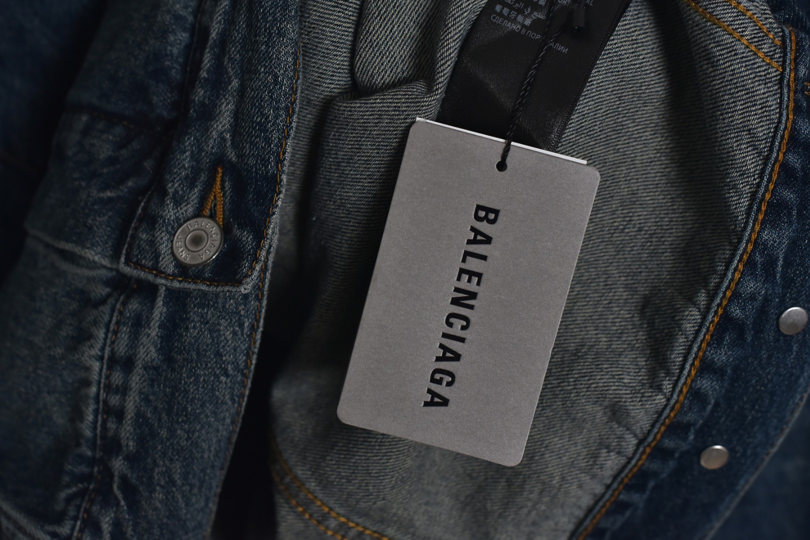 图片[4]-#Balenciaga/巴黎世家 25Fw 银胶带印花蓝牛仔外套 定制赛络纺工艺牛仔面料。此工艺使两根粗纱在纺纱阶段保持一定间距，经牵伸后由前罗拉输出，再汇合加捻成一根单纱。 赛络纺技术使最终织造出的丹宁面料具有卓越的强度、优异的耐磨性以及独特的柔软手感。纱线结构紧密，面料纹理清晰、光泽柔和，布面毛羽显著减少，呈现出普通牛仔无法比拟的细腻、挺括且高质感的视觉和触觉体验，为后续的重工艺处理提供了完美的基础。所有接缝、拼接处均采用高张力、高密度、均匀一致的针距进行缝制。线迹精准如机械制图，无任何跳针、断线或线头。内侧包边处理工整，承受高强度穿着与洗涤后仍能保持结构稳定，体现了世界级大厂对生产流程的严苛品控和无可挑剔的缝制技术。印花工艺复杂性： 这是整件外套最具技术挑战性的部分，其“胶带”效果并非普通印花或贴膜，而是采用了极为繁琐的多层厚板胶浆印花与特种闪粉混合印刷技术。厚板印刷： 通过多次重复印刷特调高分子胶浆，在面料表面堆叠出具有显著3D立体浮雕感的“胶带”条纹。每一次印刷都需经过精确对位和高温烘干定型，确保图案边缘锐利如刀刻，厚度均匀一致，手感坚硬且极具冲击力。闪粉融合： 在胶浆未完全固化前，将定制的高折射率微闪片通过精密筛网均匀撒在印花表面，并使其牢固嵌入胶浆内部。此步骤需精确控制胶浆粘度和闪粉的附着力，确保闪粉分布均匀、牢固不脱落，且光泽璀璨持久。 品质体现： 最终形成的印花图案不仅具有强烈的视觉立体感和触摸感，更因其高强度的物化特性，实现了极高的耐撕裂性、抗皱性和耐洗牢度。印花部分不会开裂、剥落或变黄，闪粉在日常穿着中也能最大限度地保持其闪耀效果，经久如新。这种工艺将装饰性与功能性推向了极致，成本高昂，良品率极低，是大厂才能驾驭的复杂技术 尺码：1 2 3-选品中心