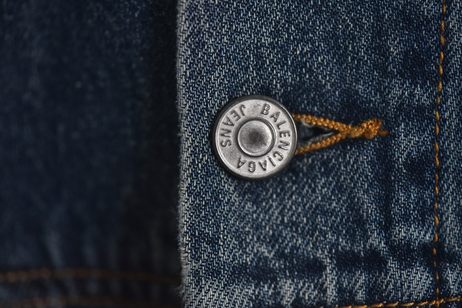 图片[3]-#Balenciaga/巴黎世家 25Fw 银胶带印花蓝牛仔外套 定制赛络纺工艺牛仔面料。此工艺使两根粗纱在纺纱阶段保持一定间距，经牵伸后由前罗拉输出，再汇合加捻成一根单纱。 赛络纺技术使最终织造出的丹宁面料具有卓越的强度、优异的耐磨性以及独特的柔软手感。纱线结构紧密，面料纹理清晰、光泽柔和，布面毛羽显著减少，呈现出普通牛仔无法比拟的细腻、挺括且高质感的视觉和触觉体验，为后续的重工艺处理提供了完美的基础。所有接缝、拼接处均采用高张力、高密度、均匀一致的针距进行缝制。线迹精准如机械制图，无任何跳针、断线或线头。内侧包边处理工整，承受高强度穿着与洗涤后仍能保持结构稳定，体现了世界级大厂对生产流程的严苛品控和无可挑剔的缝制技术。印花工艺复杂性： 这是整件外套最具技术挑战性的部分，其“胶带”效果并非普通印花或贴膜，而是采用了极为繁琐的多层厚板胶浆印花与特种闪粉混合印刷技术。厚板印刷： 通过多次重复印刷特调高分子胶浆，在面料表面堆叠出具有显著3D立体浮雕感的“胶带”条纹。每一次印刷都需经过精确对位和高温烘干定型，确保图案边缘锐利如刀刻，厚度均匀一致，手感坚硬且极具冲击力。闪粉融合： 在胶浆未完全固化前，将定制的高折射率微闪片通过精密筛网均匀撒在印花表面，并使其牢固嵌入胶浆内部。此步骤需精确控制胶浆粘度和闪粉的附着力，确保闪粉分布均匀、牢固不脱落，且光泽璀璨持久。 品质体现： 最终形成的印花图案不仅具有强烈的视觉立体感和触摸感，更因其高强度的物化特性，实现了极高的耐撕裂性、抗皱性和耐洗牢度。印花部分不会开裂、剥落或变黄，闪粉在日常穿着中也能最大限度地保持其闪耀效果，经久如新。这种工艺将装饰性与功能性推向了极致，成本高昂，良品率极低，是大厂才能驾驭的复杂技术 尺码：1 2 3-选品中心