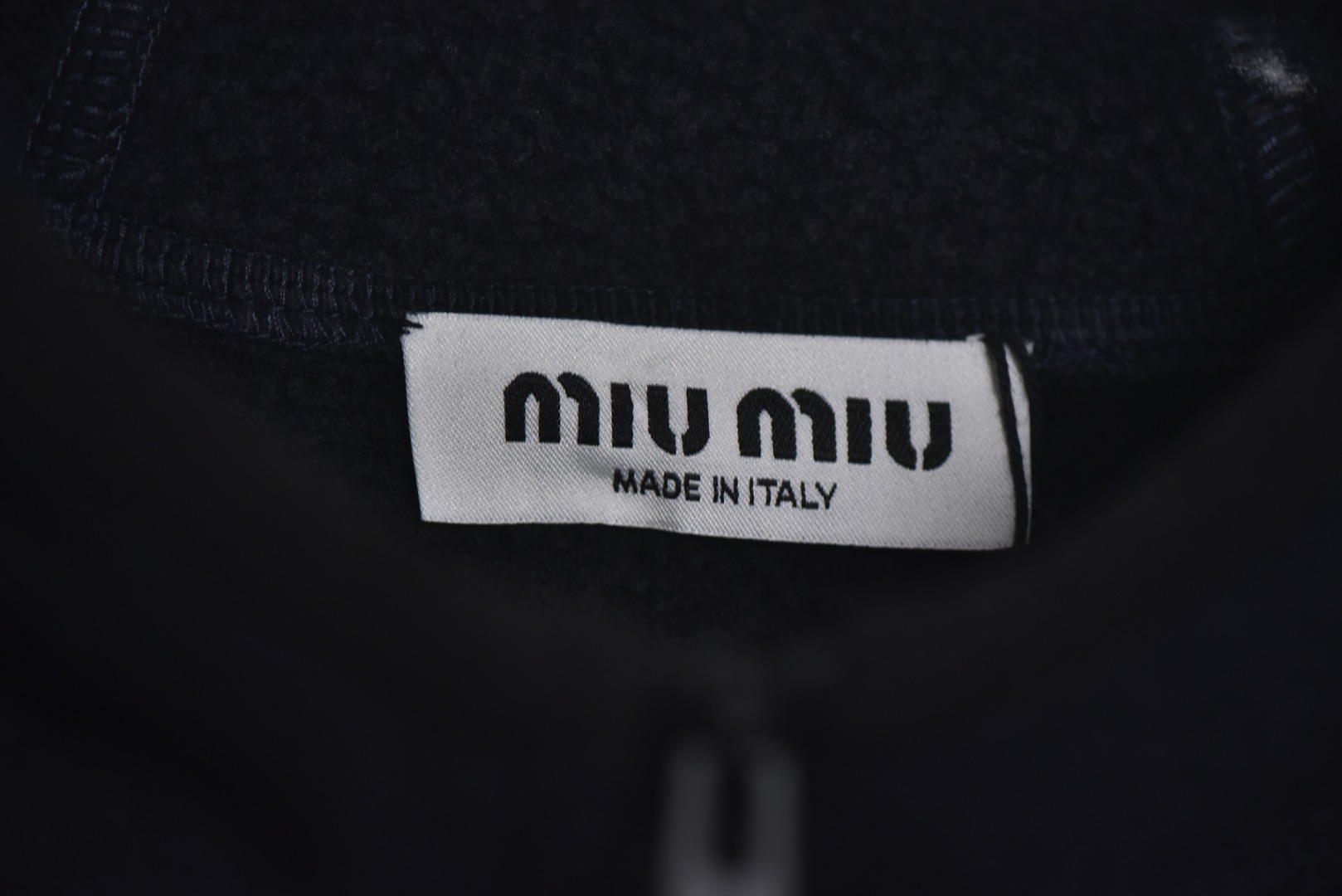 图片[7]-#Miu Miu 25Fw Miu小标摇粒绒连帽外套 面料采用定制织造染整一体工艺，从纱线选配到染色均按品牌标准定制。400克重摇粒绒需平衡蓬松度与垂感，通过经纬密优化确保厚度一致且抗风保暖。色牢度控制：定染环节采用环保活性染料，经5次水洗测试确保色彩零偏差，实现桃粉、薄荷绿等高饱和度色调的纯净度。肌理处理：双刷双摇工艺打造绒毛丰盈且定向倒伏的立体质感，避免传统摇粒绒的臃肿感。全件拉链及配件均为开模定制，非市场公版零件。拉链齿工艺：采用哑光涂层YKK EXCELLA系列，顺滑度与耐久度超越工业标准，拉头内部结构加入消音硅脂。挂绳挂件设计：拉链片与挂绳采用超声波切割无缝拼接，尾端缀以激光雕刻Miu Logo的锌合金吊坠，单挂件经历12道冲压打磨工序。装饰刺绣均采用进口田岛多针头绣花机完成。3D立体绣法：先以平绣打底，再叠加链目绣与毛巾绣混合工艺，使图案凸起高度达1.2mm，触感柔软不硌肤。本品以工艺冗余度换取极致体验，从纱线定制到终端装配均执行高精度标准，将功能性细节转化为隐性奢华，重构时尚单品的价值维度 尺码：S-L-选品中心