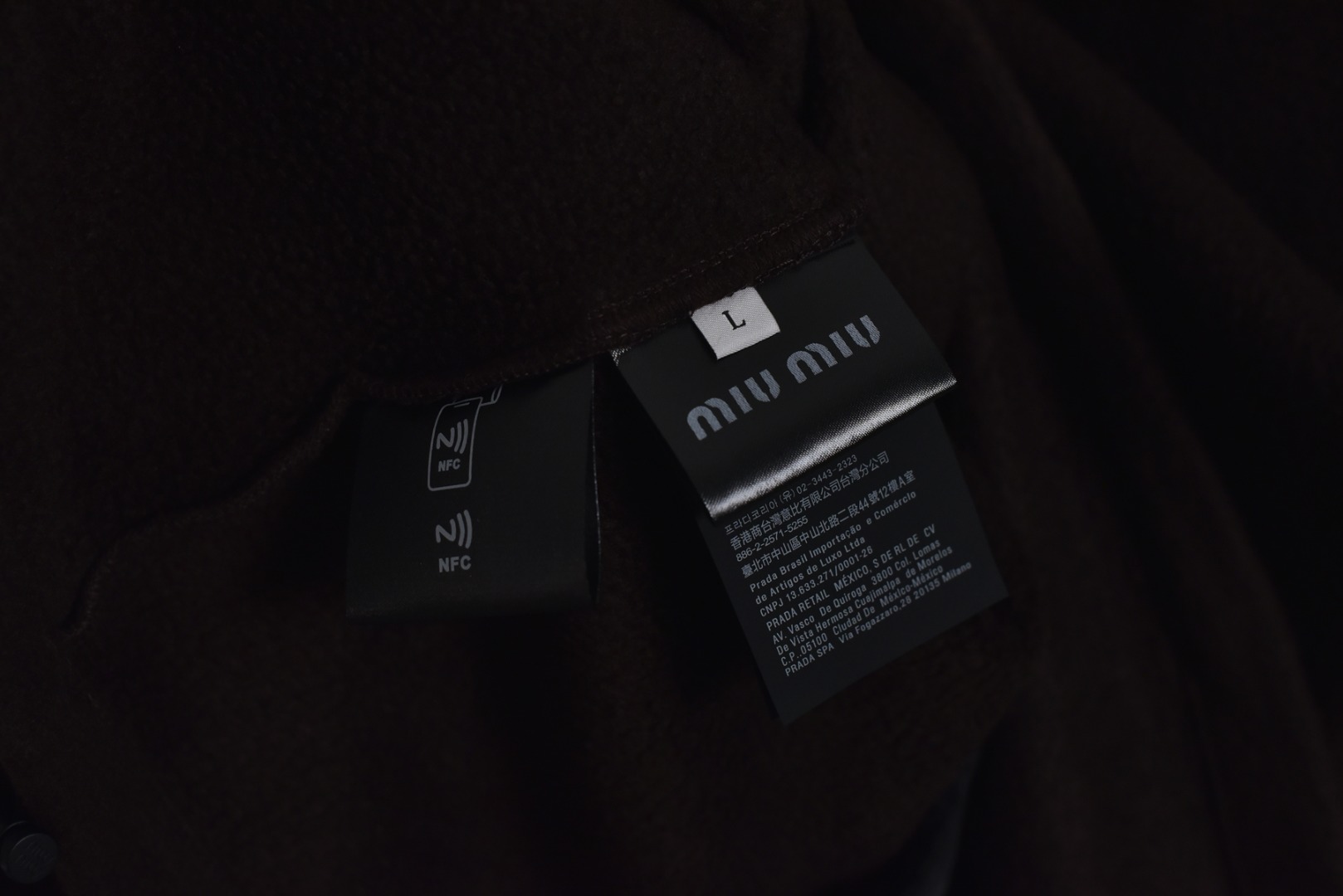 图片[8]-#Miu Miu 25Fw Miu小标咖色摇粒绒立领外套 面料采用定制织造染整一体工艺，从纱线选配到染色均按品牌标准定制。400克重摇粒绒需平衡蓬松度与垂感，通过经纬密优化确保厚度一致且抗风保暖。色牢度控制：定染环节采用环保活性染料，经5次水洗测试确保色彩零偏差，实现桃粉、薄荷绿等高饱和度色调的纯净度。肌理处理：双刷双摇工艺打造绒毛丰盈且定向倒伏的立体质感，避免传统摇粒绒的臃肿感。全件拉链及配件均为开模定制，非市场公版零件。拉链齿工艺：采用哑光涂层YKK EXCELLA系列，顺滑度与耐久度超越工业标准，拉头内部结构加入消音硅脂。挂绳挂件设计：拉链片与挂绳采用超声波切割无缝拼接，尾端缀以激光雕刻Logo的锌合金吊坠，单挂件经历12道冲压打磨工序。装饰刺绣均采用田岛多针头绣花机完成。3D立体绣法：先以平绣打底，再叠加链目绣与毛巾绣混合工艺，使图案凸起高度达1.2mm，触感柔软不硌肤。本品以工艺冗余度换取极致体验，从纱线定制到终端装配均执行高精度标准，将功能性细节转化为隐性奢华，重构时尚单品的价值维度 尺码：S-L-选品中心