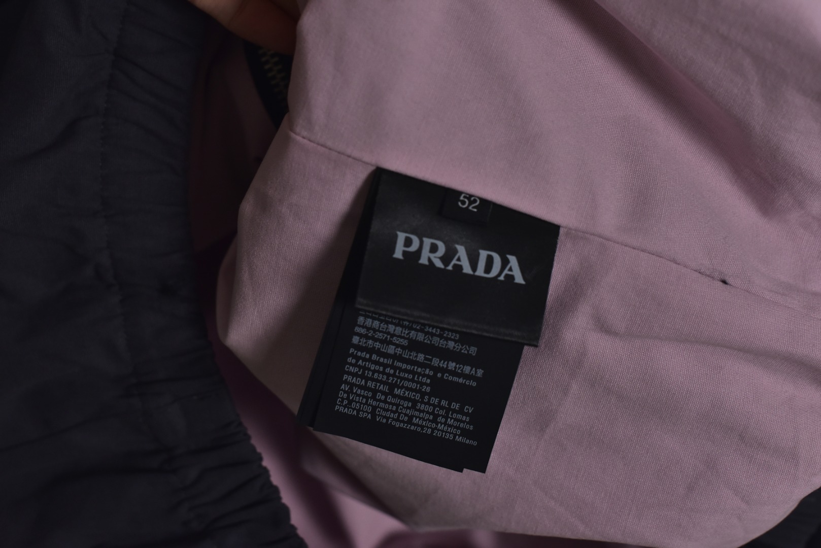 图片[6]-#Prada/普拉达 25Fw 小标灰粉夹克外套 定织高支高密的全工艺梭织面料，经纱与纬纱均采用精梳长绒棉与微量高科技聚酯纤维混纺，通过调整织机参数和纱线张力，使面料呈现出细腻、致密且硬挺的质感。其表面有极其细微的肌理感，而非普通面料的平淡光泽。这种密度确保了夹克廓形的立挺度与持久性，久穿不易变形。定染面料，“哈灵顿灰粉” 并非普通的粉灰色，而是经过多次校色实验的复合色调。在灰色的冷峻基调中，精准注入了一抹低饱和度的粉彩，形成了冷静克制与温柔浪漫的独特冲突感。染料采用进口环保染料，经过先染后整的工艺，色牢度极高，颜色渗透至纤维内核，确保了色彩的持久与均匀，杜绝了廉价面料的浮色感。“重机”JUKI专业缝纫设备。使用特定针距确保线迹均匀、牢固且美观。接缝均采用包边处理，完全看不到毛边，关键受力点均进行二次打结或强化，极大提升了耐用性。使用田岛多头电子刺绣机，以超过每分钟1000转的高速和0.1mm的精度还原，每一个字母的转角、弧线的边缘都清晰锐利，无任何锯齿感。定制辅料三标，男女同款 尺码：48 50 52-选品中心