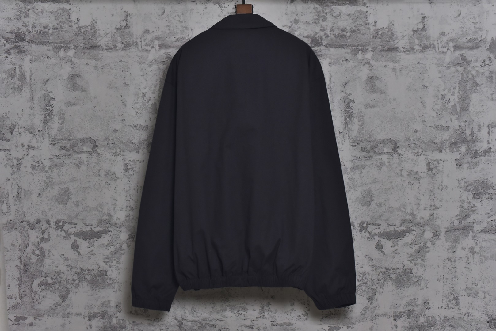 图片[2]-#Prada/普拉达 25Fw 小标灰粉夹克外套 定织高支高密的全工艺梭织面料，经纱与纬纱均采用精梳长绒棉与微量高科技聚酯纤维混纺，通过调整织机参数和纱线张力，使面料呈现出细腻、致密且硬挺的质感。其表面有极其细微的肌理感，而非普通面料的平淡光泽。这种密度确保了夹克廓形的立挺度与持久性，久穿不易变形。定染面料，“哈灵顿灰粉” 并非普通的粉灰色，而是经过多次校色实验的复合色调。在灰色的冷峻基调中，精准注入了一抹低饱和度的粉彩，形成了冷静克制与温柔浪漫的独特冲突感。染料采用进口环保染料，经过先染后整的工艺，色牢度极高，颜色渗透至纤维内核，确保了色彩的持久与均匀，杜绝了廉价面料的浮色感。“重机”JUKI专业缝纫设备。使用特定针距确保线迹均匀、牢固且美观。接缝均采用包边处理，完全看不到毛边，关键受力点均进行二次打结或强化，极大提升了耐用性。使用田岛多头电子刺绣机，以超过每分钟1000转的高速和0.1mm的精度还原，每一个字母的转角、弧线的边缘都清晰锐利，无任何锯齿感。定制辅料三标，男女同款 尺码：48 50 52-选品中心