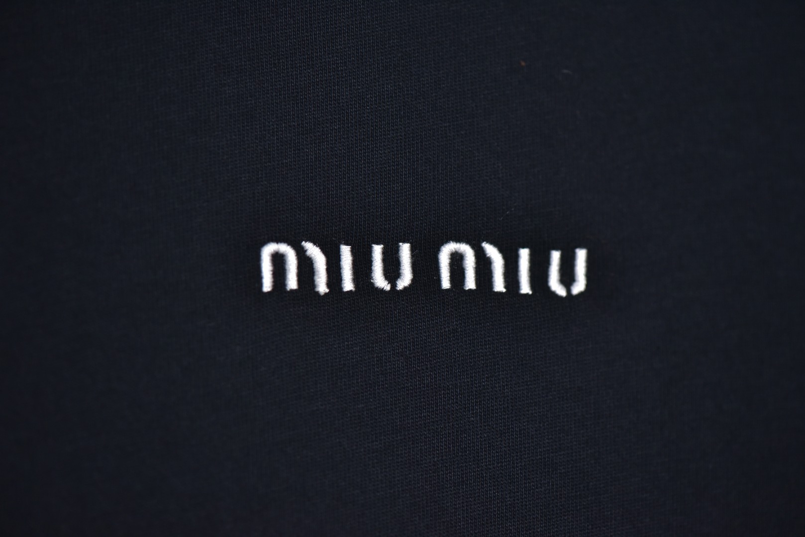 图片[3]-#Miu Miu 25Fw Miu小标刺绣长袖 采用高品级24支精梳棉纱线，通过「先染后织」工艺确保色彩均匀性，纱线经双股加捻提升抗起球性，布面光洁度优于普通棉织物，对版190克重精密调控：通过18针细针距圆机编织，兼顾垂坠感与挺括性，需配合恒温恒湿车间避免纱线张力波动，紧密纺结构：借鉴瑞士立达紧密纺技术，纱线毛羽减少60%，织物密度达156针/英寸²，实现婴儿肌肤触感的同时保持8%以上的弹性回复率，采用日本FIL-TEC刺绣专用涤纶线，实用进口田岛机设备，确保每英寸12针的高密度刺绣图案边缘无毛刺，底层先以水溶衬定位，中层填充天丝垫纱，表层以雕孔绣工艺打造空气感立体效果，定制辅料三标，男女同款 尺码：XS-M-选品中心