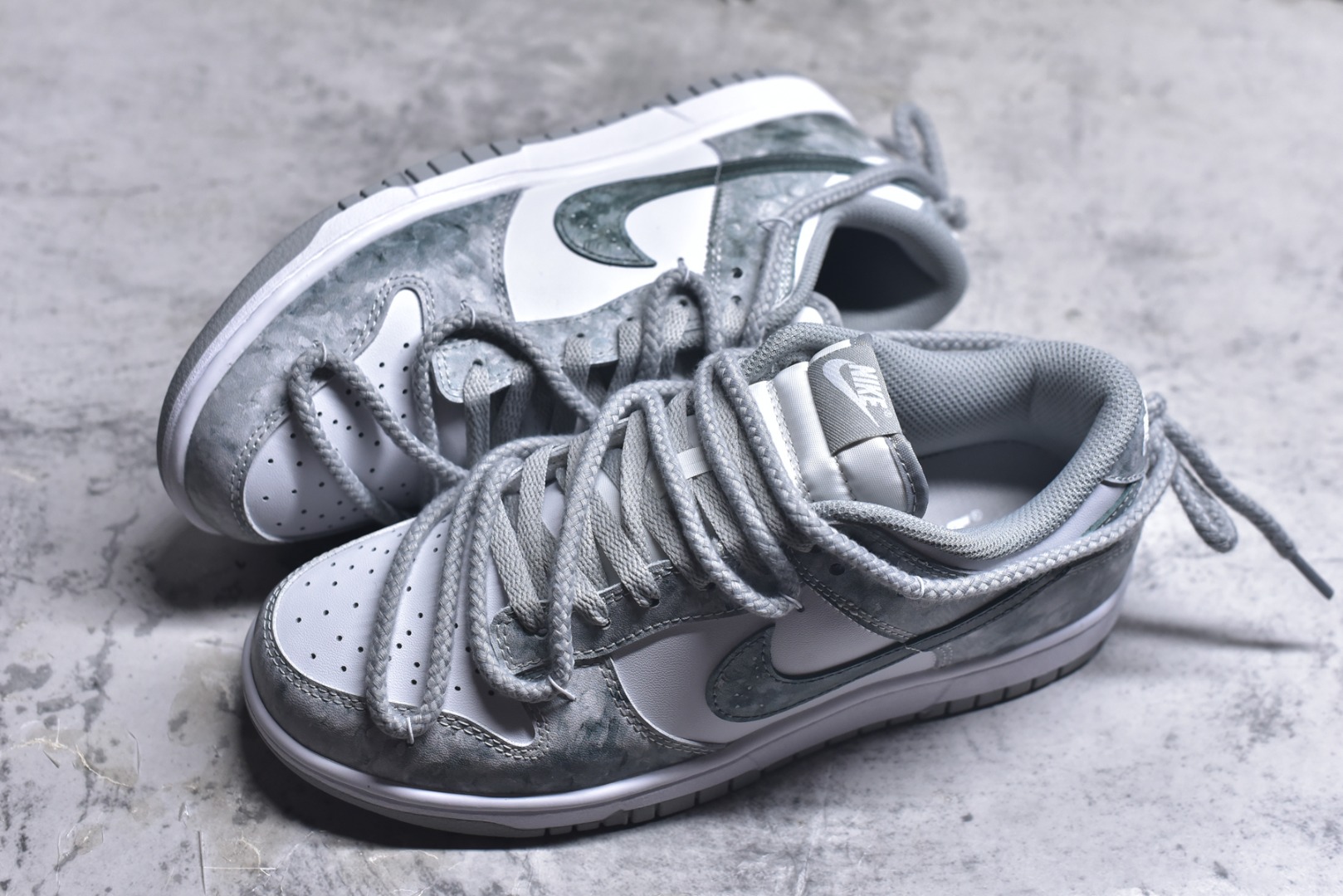 图片[7]-#Nike Dunk Low 凝灰纪元 灰色 鞋身以纯白为画布，如初雪覆盖的旷野，而迷彩般的灰纹肆意蔓延，赋予鞋面立体触感与地质张力。侧身Swoosh以哑光灰低调勾勒，恰如暗藏于纪元深处的符号印记。灰度并非单调，而是层次的艺术：当岩石的肌理落入初雪之境，从浅灰的朦胧到深灰的锐利，以灰度美学重新定义你的穿搭法则。 货号： HF5441-105 尺码： 40 40.5 41 42 42.5 43 44 44.5 45 46-选品中心