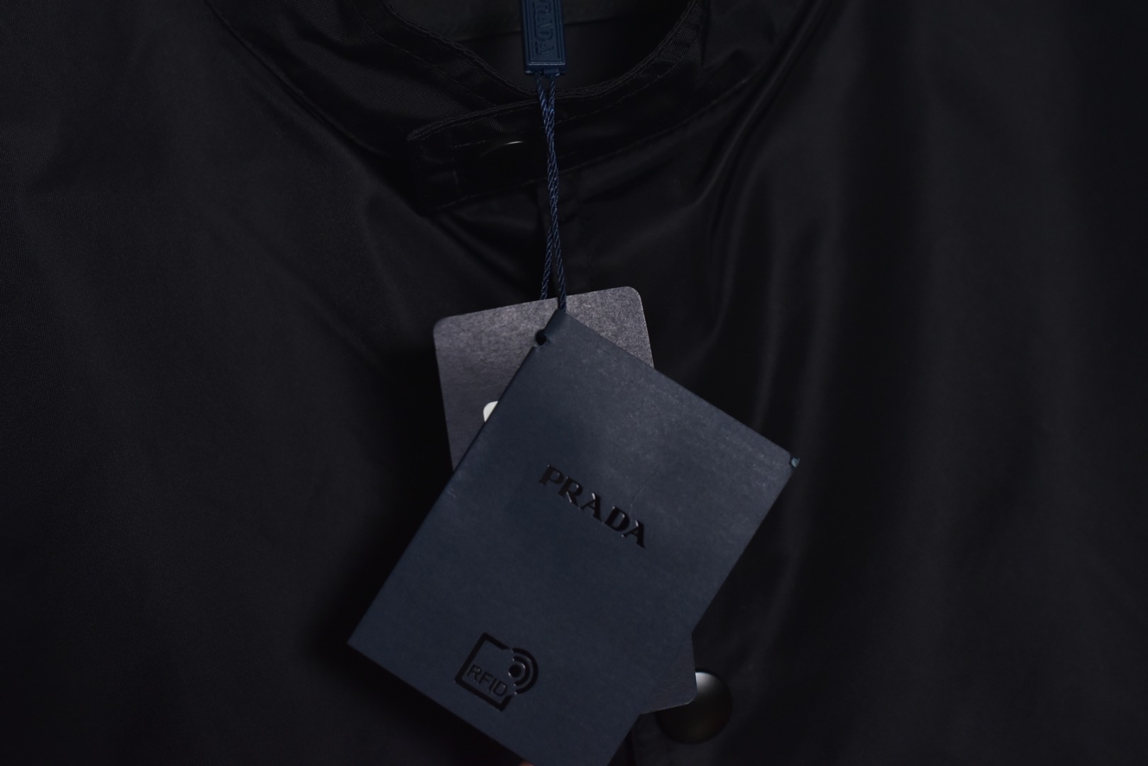 图片[4]-#Prada/普拉达 25Fw 双口袋三角标夹克外套 面料为特殊定制的高密度再生尼龙，并非市场普通现货，其密度、手感与防泼水性能均对标原版，力求还原Re-Nylon材质的轻盈质感与耐磨特性，原版面料重量精密控制在600-800克之间​（视款式而定），本品同样追求这种轻盈与挺括的平衡。所有五金件（包括拉链、扣具等）均源自东莞专业的箱包五金供应商，绝非普通市场通货，五金质感顺滑，经久耐用，拉链头顺滑度优异，减少卡顿感，与原版追求的耐用性一脉相承。胸前标志性的涂珐琅三角形金属徽标，采用的是与原厂（Prada供应商）一致的KF镜面三角标。此徽标由价值千万元的专用机器制作，呈现出镜面效果与清晰字体，细节精度远超市场仿品。原版徽标同样注重质感，其珐琅涂层通过盐雾测试，长期使用不易氧化。三标与洗标均为按原版材质定制，手感与材质均力求一致，确保细节处的正宗感。原版夹克在缝线工艺上采用双层缝线，拼接处使用隐藏式针脚，以提升耐用性和美观性，男女同款 尺码：46 48 50 52-选品中心