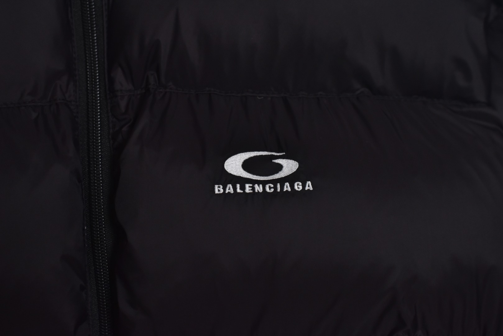 图片[3]-#Balenciaga/巴黎世家 25Fw 圆环小标棉服外套 定制开发高支高密梭织面料，是其高级质感的基石，高支数意味着纱线极细，从而织出纹理细腻、触感丝滑的表面，高密度则赋予了面料出色的挺括度、耐磨性与抗风能力，它避免了普通棉帆布的粗糙感，呈现出一种低调而精准的微光泽，为后续的刺绣与包边工艺提供了完美且稳定的基础，填充物选用珍珠棉，这是一种中空三维卷曲纤维，相比传统絮片，珍珠棉能提供更持久、均匀的蓬松感与回弹性，确保轮廓饱满不塌陷，中空结构可以锁住空气，实现最佳保暖重量比，达成“轻盈如羽，温暖如裘”的穿着体验，填充工艺需确保棉体在绗缝格内均匀分布，无空洞或结块，这要求极高的充绒精度。在此单品中，所有裁片边缘均采用斜裁包边条进行全方位包裹。这并非简单的锁边。高密度针迹，采用数万针的高密度刺绣，图案饱满立体，边缘清晰锐利，无任何松散线头，底层面料稳定处理，在如此轻薄高密的面料上进行密集刺绣，极易导致面料收缩变形，会在刺绣底层使用特制水溶衬或热熔衬，刺绣完成后这些衬布会消失，从而确保图案平整挺括，且不破坏面料本身的柔韧度。这是对手工与科技结合的极致考验，定制辅料三标，男女同款 尺码：XS-M-选品中心