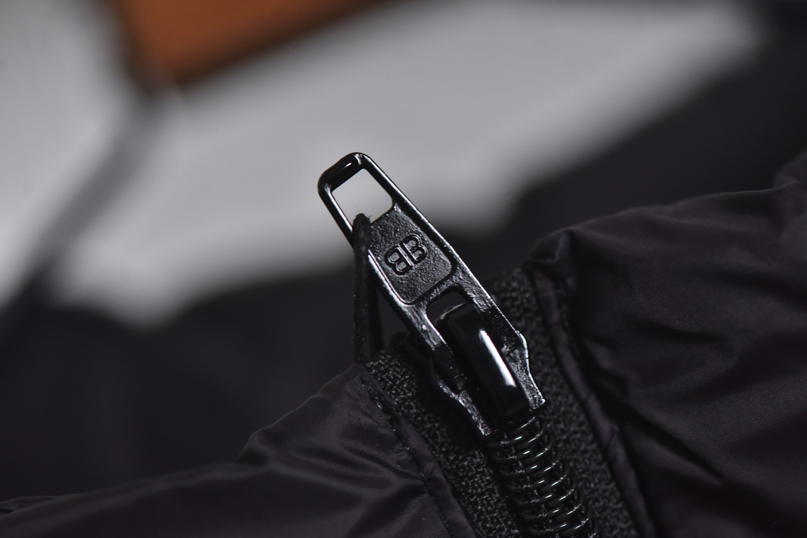 图片[7]-#Balenciaga/巴黎世家 25Fw 圆环小标棉服外套 定制开发高支高密梭织面料，是其高级质感的基石，高支数意味着纱线极细，从而织出纹理细腻、触感丝滑的表面，高密度则赋予了面料出色的挺括度、耐磨性与抗风能力，它避免了普通棉帆布的粗糙感，呈现出一种低调而精准的微光泽，为后续的刺绣与包边工艺提供了完美且稳定的基础，填充物选用珍珠棉，这是一种中空三维卷曲纤维，相比传统絮片，珍珠棉能提供更持久、均匀的蓬松感与回弹性，确保轮廓饱满不塌陷，中空结构可以锁住空气，实现最佳保暖重量比，达成“轻盈如羽，温暖如裘”的穿着体验，填充工艺需确保棉体在绗缝格内均匀分布，无空洞或结块，这要求极高的充绒精度。在此单品中，所有裁片边缘均采用斜裁包边条进行全方位包裹。这并非简单的锁边。高密度针迹，采用数万针的高密度刺绣，图案饱满立体，边缘清晰锐利，无任何松散线头，底层面料稳定处理，在如此轻薄高密的面料上进行密集刺绣，极易导致面料收缩变形，会在刺绣底层使用特制水溶衬或热熔衬，刺绣完成后这些衬布会消失，从而确保图案平整挺括，且不破坏面料本身的柔韧度。这是对手工与科技结合的极致考验，定制辅料三标，男女同款 尺码：XS-M-选品中心