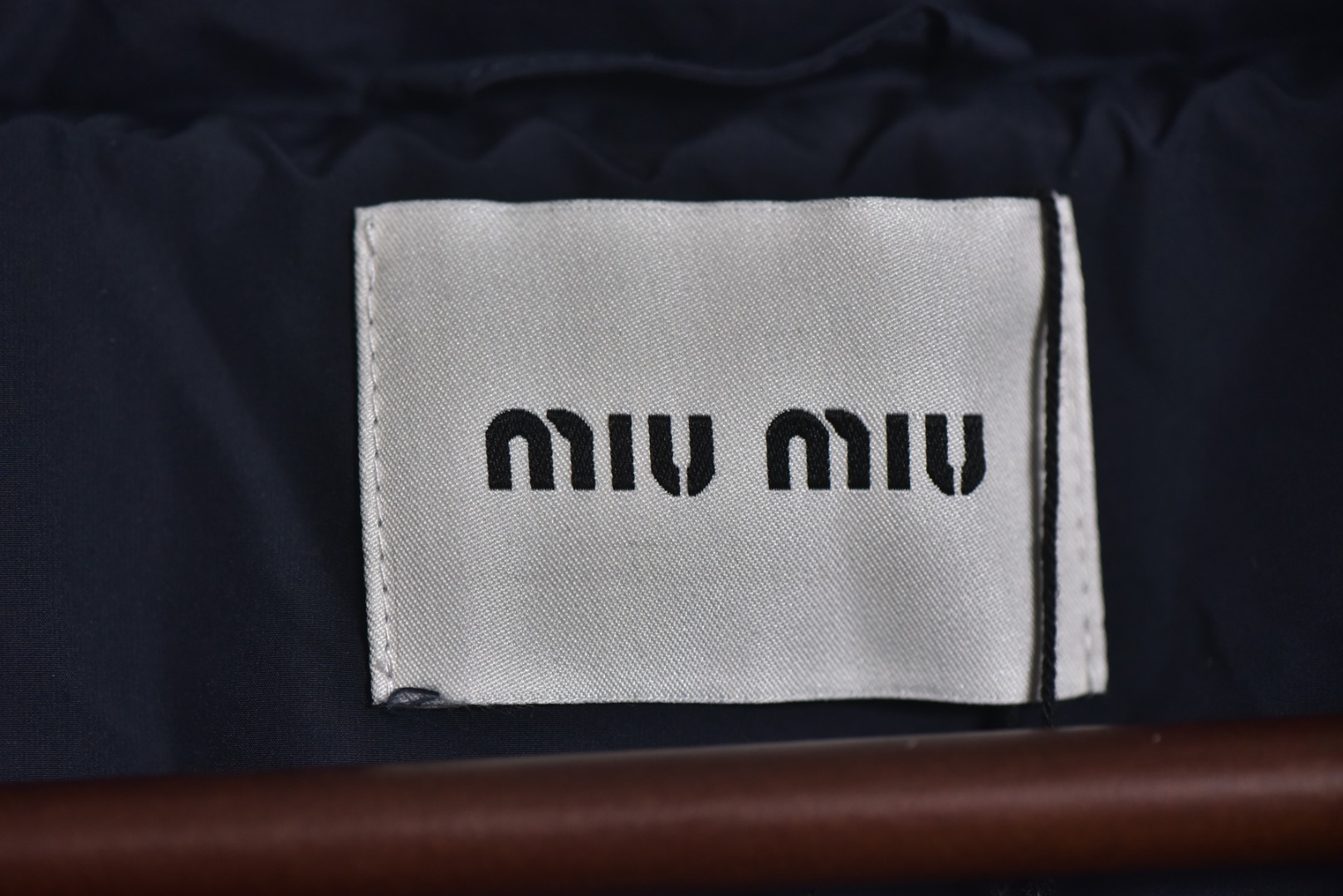 图片[7]-#Miu Miu 25Fw Miu小标捆条短款羽绒服 -核心内里填充180G广检认证90%纯白鸭绒 定制开发高支高密梭织面料，其纱线结构与织法经过精密计算，旨在实现极佳的防绒钻性，同时保证面料本身的轻盈与耐久度，面料色彩为独家定染，确保了色彩的纯粹度与独特性，采用捆条拼接工艺，该工艺在每块裁片的接缝处内衬一条白色织带，再将面料拼接并压线固定，白色的捆条在深色面料上形成了鲜明而利落的轮廓线，强化了单品的结构化视觉，内里填充90白鸭绒，高纯度绒子能锁住大量空气，形成静止空气层，实现高效保暖，这使得羽绒服在拥有极强保暖性的同时，重量得以大幅减轻，选用进口电脑充绒设备，确保每一个独立绗格内的羽绒填充量都精准、均匀，避免出现局部空洞或结块，从而保证羽绒服整体的平整度、保暖均匀性与持久蓬松，定制辅料三标 尺码：38 40 42-选品中心