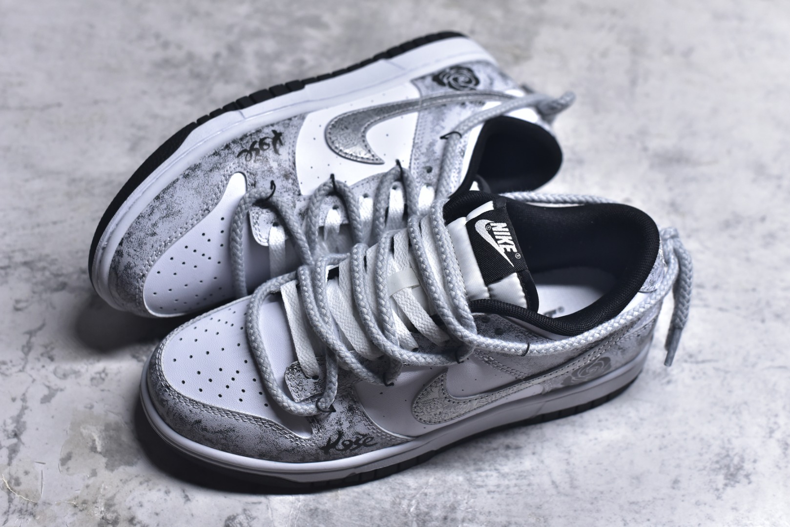 图片[7]-#NK Dunk Low 银绽 DD1391-100 银霜为序，玫瑰为诗，当低调的白，邂逅泼墨般的银灰，仿佛寒夜凝结的霜华在鞋面悄然绽放，在光影流转间暗藏层次，呼应「银绽」之名。粗绳鞋带束起利落轮廓，侧身的黑色玫瑰，以暗纹刺绣悄然盛放，注入一抹不羁的浪漫基因。定制系列天花板 无原鞋不开发 全系列得物原鞋一比一校对开发 配色持续更新中 终端对接 优势输出 全套原厂楦头原纸板数据档案倾力打造 原汁原味莞产 极致还原 圈内最强针车工艺 高端零售指定版 广东原厂配套原盒原标 鞋盒分三个尺码段 原厂冲刀 超高清洁度 全鞋零毛边皮料切割 采用原厂百宏鞋带以及原厂百宏织唛舌标 内标可供原厂几率过验 进口原装条纹中底布 四线拉帮白色点胶 原厂拉帮手法遵循公司 原厂电绣 极致还原 SIZE 40 40.5 41 42 42.5 43 44 44.5 45 46-选品中心