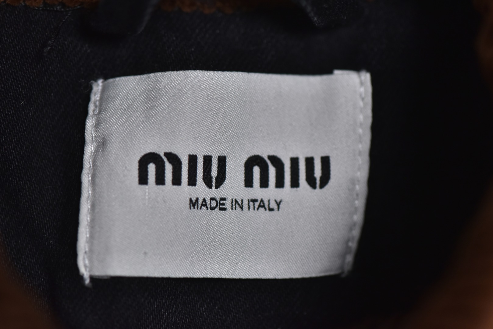 图片[5]-#Miu Miu 25Fw Miu小标牛仔棉服外套 选用高克重100%棉制牛仔斜纹布，高克重意味着面料单位面积密度更高，这不仅赋予了服装卓越的耐用性与抗皱性，更关键的是，它能自然支撑起利落而硬挺的立体廓形，无需依赖额外的内衬，面料经过专业的洗水处理，通过精准控制的酶洗、石磨等工艺，软化了原生棉布的僵硬感，使其触感更为亲肤柔顺。同时，这一过程赋予了丹宁独特的落色效果与微妙的复古做旧纹理，领部采用100%纯棉粗棱灯芯绒，其独特的瓦楞状脊线纹理与主体丹宁的斜纹肌理形成强烈而巧妙的视觉与触觉对比，将柔软且结构相对松散的灯芯绒与硬挺的牛仔布进行拼接，需要极高的裁切与缝纫精度，以确保接缝处平整牢固，避免因材质缩率不同而产生的变形。此举体现了品牌对异材质拼接工艺的成熟掌控，内里填充1400D高密度洗水棉。这里的“D”并非填充重量，而是指棉絮本身的纤维细度与长度规格，其拥有极佳的蓬松度与持久性，不易结块或移位，能确保夹克长期使用后仍保持均匀平整的保暖层，结合高克重牛仔布形成的“外壳结构”，共同构建了一个轻量却高效的隔热系统，实现了保暖性与廓形感的统一，在左前幅，运用了极为精细的真皮激光镭射雕花工艺。首先将一块小牛皮复合于面料之上，随后通过高精度激光按照预设图案进行烧蚀，刻画出品牌标识或图案，此工艺要求对激光的功率与速度进行毫厘不差的控制，才能在皮革上实现边缘锐利、细节分明的图案，同时不伤及底层的丹宁面料，定制辅料三标，男女同款 尺码：40 42 44-选品中心