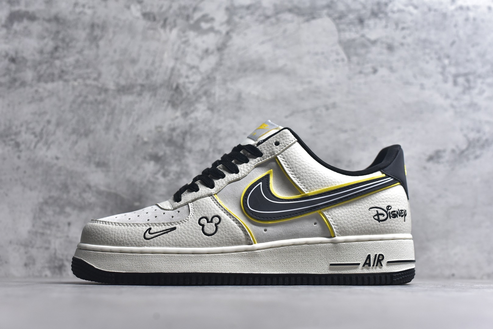 #童趣奢潮碰撞！AF1 Low x Disney 联名款唤醒童年DNA 当Nike Air Force 1 Low的经典街头骨架遇上迪士尼的童话基因，这双SY1388-021联名款直接把「潮玩童趣」焊在了鞋面上！ 鞋身以奶白荔枝纹皮革搭配浅灰磨砂皮打造基底，黑黄撞色的Swoosh线条利落又俏皮，黄色包边如漫画描边般勾勒出灵动质感。鞋头的米奇轮廓简笔画、鞋侧的Disney手写体标识，将迪士尼的经典元素以手绘风呈现，细节处满是童真巧思；黑白撞色鞋带搭配经典AF1中底的「AIR」标识，保留了空军一号的街头底蕴，让童趣与潮流实现完美平衡。 作为AF1与迪士尼的跨界联名，这双鞋既延续了Air Force 1 Low的百搭属性，又凭借迪士尼的IP加持成为吸睛利器。不管是日常出街打造甜酷造型，还是作为迪士尼粉丝的收藏款，这双AF1 Low x Disney联名款都能让你在潮流圈玩转出独特的童趣风格，属于大人的童话潮鞋，入手即解锁双倍快乐！ 尺码：36-45-选品中心