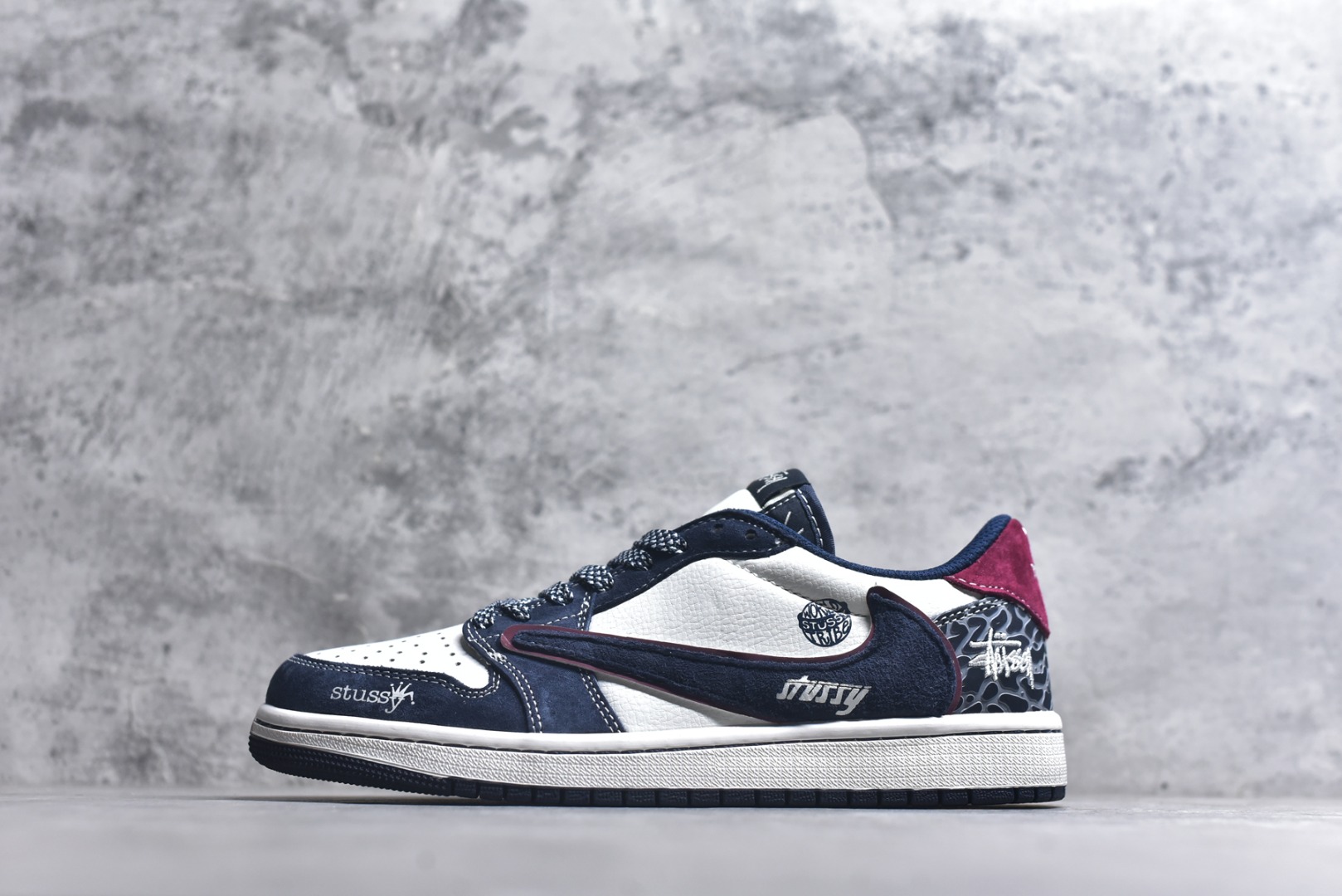 #街头联名，潮范拉满！当Air Jordan 1 Low的传奇鞋型邂逅Stüssy的街头灵魂，这双DZ5899-039联名款成为潮圈瞩目的重磅之作。 藏蓝与纯白的经典撞色打底，细腻的翻毛皮材质勾勒出鞋身的高级质感，酒红线条的点缀瞬间打破沉闷，让视觉层次更具张力。鞋侧的Stüssy字母印花、标志性的品牌吊坠，搭配鞋跟处的迷彩纹路与品牌标识，每一处细节都镌刻着街头潮牌的不羁个性，倒钩设计更是将潮流巧思拉满。经典的AJ1 Low鞋型保留了复古篮球的基因，又因Stüssy的注入焕发出浓郁的街头潮流气息。无论是搭配工装裤打造美式街头风，还是配牛仔裤诠释休闲潮范，这双鞋都能轻松成为造型核心，让你在潮搭中轻松脱颖而出。 尺码：36-45-选品中心