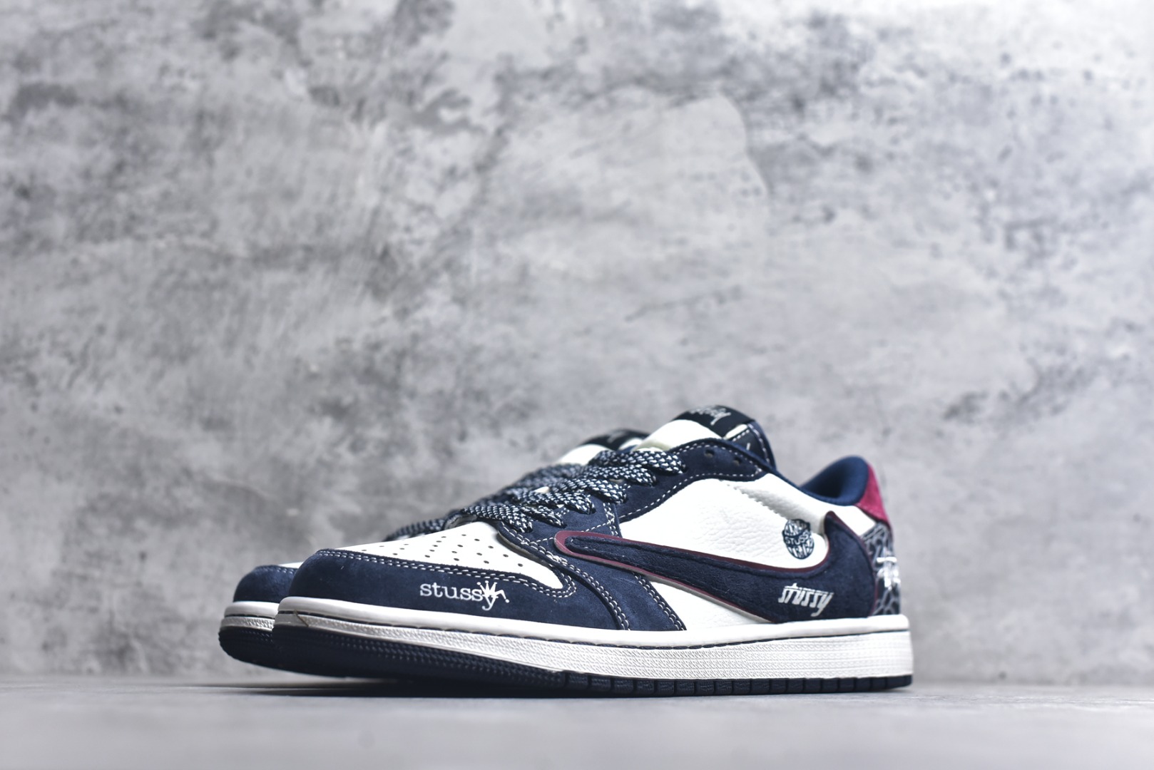 图片[2]-#街头联名，潮范拉满！当Air Jordan 1 Low的传奇鞋型邂逅Stüssy的街头灵魂，这双DZ5899-039联名款成为潮圈瞩目的重磅之作。 藏蓝与纯白的经典撞色打底，细腻的翻毛皮材质勾勒出鞋身的高级质感，酒红线条的点缀瞬间打破沉闷，让视觉层次更具张力。鞋侧的Stüssy字母印花、标志性的品牌吊坠，搭配鞋跟处的迷彩纹路与品牌标识，每一处细节都镌刻着街头潮牌的不羁个性，倒钩设计更是将潮流巧思拉满。经典的AJ1 Low鞋型保留了复古篮球的基因，又因Stüssy的注入焕发出浓郁的街头潮流气息。无论是搭配工装裤打造美式街头风，还是配牛仔裤诠释休闲潮范，这双鞋都能轻松成为造型核心，让你在潮搭中轻松脱颖而出。 尺码：36-45-选品中心