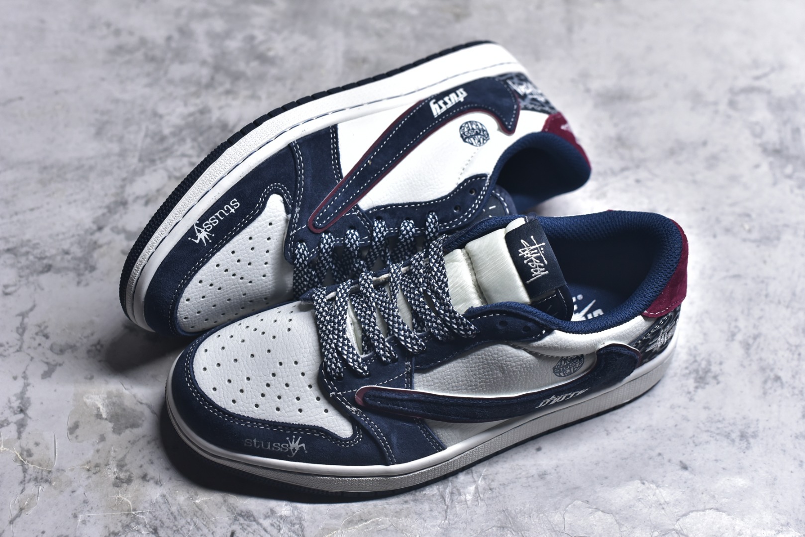 图片[7]-#街头联名，潮范拉满！当Air Jordan 1 Low的传奇鞋型邂逅Stüssy的街头灵魂，这双DZ5899-039联名款成为潮圈瞩目的重磅之作。 藏蓝与纯白的经典撞色打底，细腻的翻毛皮材质勾勒出鞋身的高级质感，酒红线条的点缀瞬间打破沉闷，让视觉层次更具张力。鞋侧的Stüssy字母印花、标志性的品牌吊坠，搭配鞋跟处的迷彩纹路与品牌标识，每一处细节都镌刻着街头潮牌的不羁个性，倒钩设计更是将潮流巧思拉满。经典的AJ1 Low鞋型保留了复古篮球的基因，又因Stüssy的注入焕发出浓郁的街头潮流气息。无论是搭配工装裤打造美式街头风，还是配牛仔裤诠释休闲潮范，这双鞋都能轻松成为造型核心，让你在潮搭中轻松脱颖而出。 尺码：36-45-选品中心