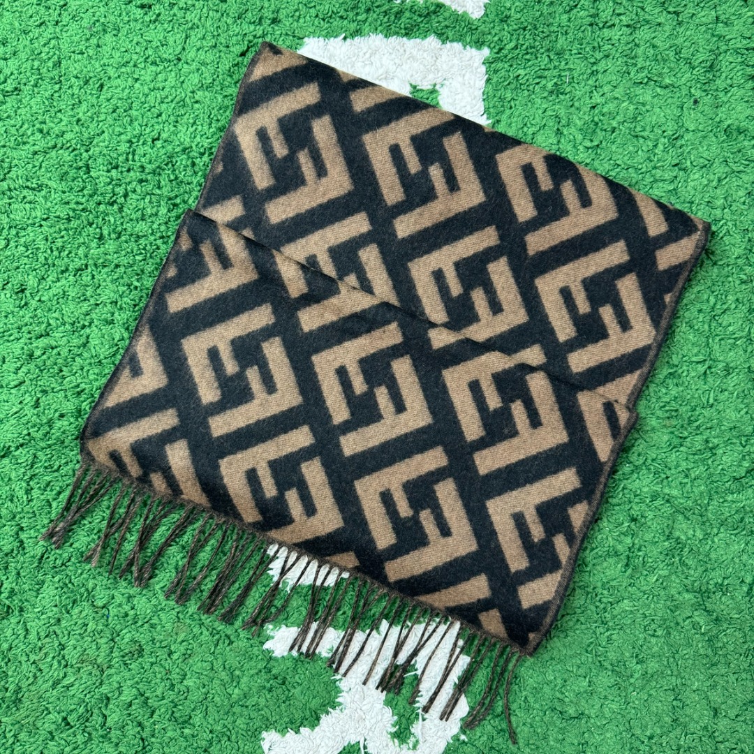 #Fendi/芬迪 FF老花流苏围巾 严格采用原版规格面料，95%优质羊毛+5%桑蚕丝混纺，得益于精梳工艺与高密度织法，围巾手感软糯亲肤，触感细腻不扎人，同时保证了面料的挺括度和垂坠感，实现了柔软与有型的完美平衡，双面可用设计，一面是深邃神秘的黑色底FF老花，另一面是温暖经典的驼色底FF老花，一条围巾相当于两种风格，随心切换，从水洗标、内标到吊牌、编号，均为一致，标签字体、缝线工艺等细节均严格对标，超大尺寸既可作围巾，也可当披肩，FF老花图案是品牌最具辨识度的视觉符号，自带高级气场，能瞬间提升整体穿搭的时尚感，让日常造型“UpUp” 尺码：180×48cm，流苏10cm-选品中心