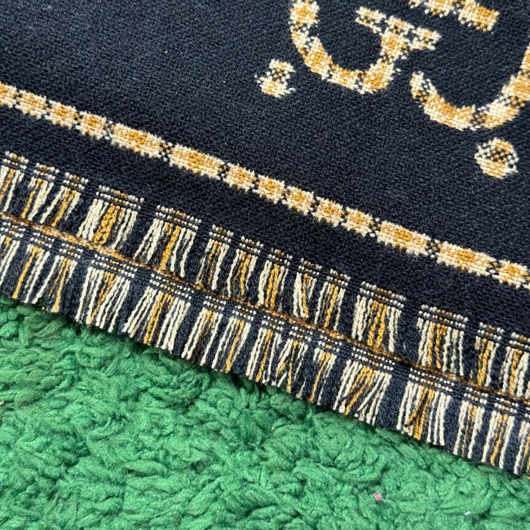 图片[5]-#Gucci/古驰 黑金双G流苏围巾 围巾采用双面设计，一面饰有经典的GG老花图案，另一面则是简约素色，相当于一条围巾的价格，获得两种不同的穿搭风格，细节上，烫金元素或细碎金线的加入，打破了秋冬的沉闷感，在不经意间透露出低调的高级感，超大尺寸让它远超普通围巾的功能，你可以轻松地将其作为披肩搭配，增添大气场，也可以绕颈一两次，打造慵懒而精致的层次感。由于其足够宽大厚实，在微凉天气里完全可以作为一件时尚的小外套使用，真正实现“凹造型与保暖”兼得，围巾采用100%新剪羊毛，材质本身具有优异的保暖性，经过巴素兰工艺处理，触感软糯亲肤，避免了普通羊毛的扎刺感 尺码：180×49cm，流苏2cm-选品中心