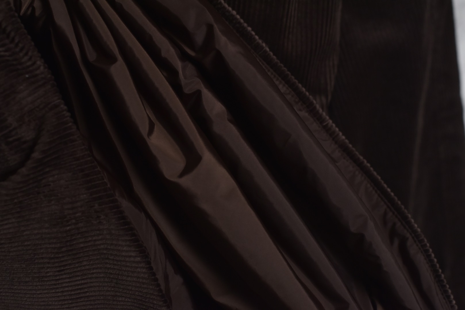 图片[10]-#PRD灯芯绒贴布棉服 深棕色 乌木色款为100%棉 填充层为55%再生聚酯纤维+45%聚酯纤维 采用Prada 2025秋冬新配方 将传统灯芯绒克重从380g/㎡降至260g/㎡ 兼顾透气性与挺括度 经纱选用28tex×2（21/2英支）股线 纬纱为28tex（21英支）单纱 符合高端灯芯绒纱线规格 成品克重260g/㎡ 属于轻盈型灯芯绒 绒条细腻且回弹无褶 整体采用压胶工艺替代传统平车踩线，接缝处密封性好，且减少线迹磨损风险 面料经过预洗水+软整理 绒面手感柔软且无浮色 色牢度达ISO 105标准4级以上 尺码：XS S M L-选品中心