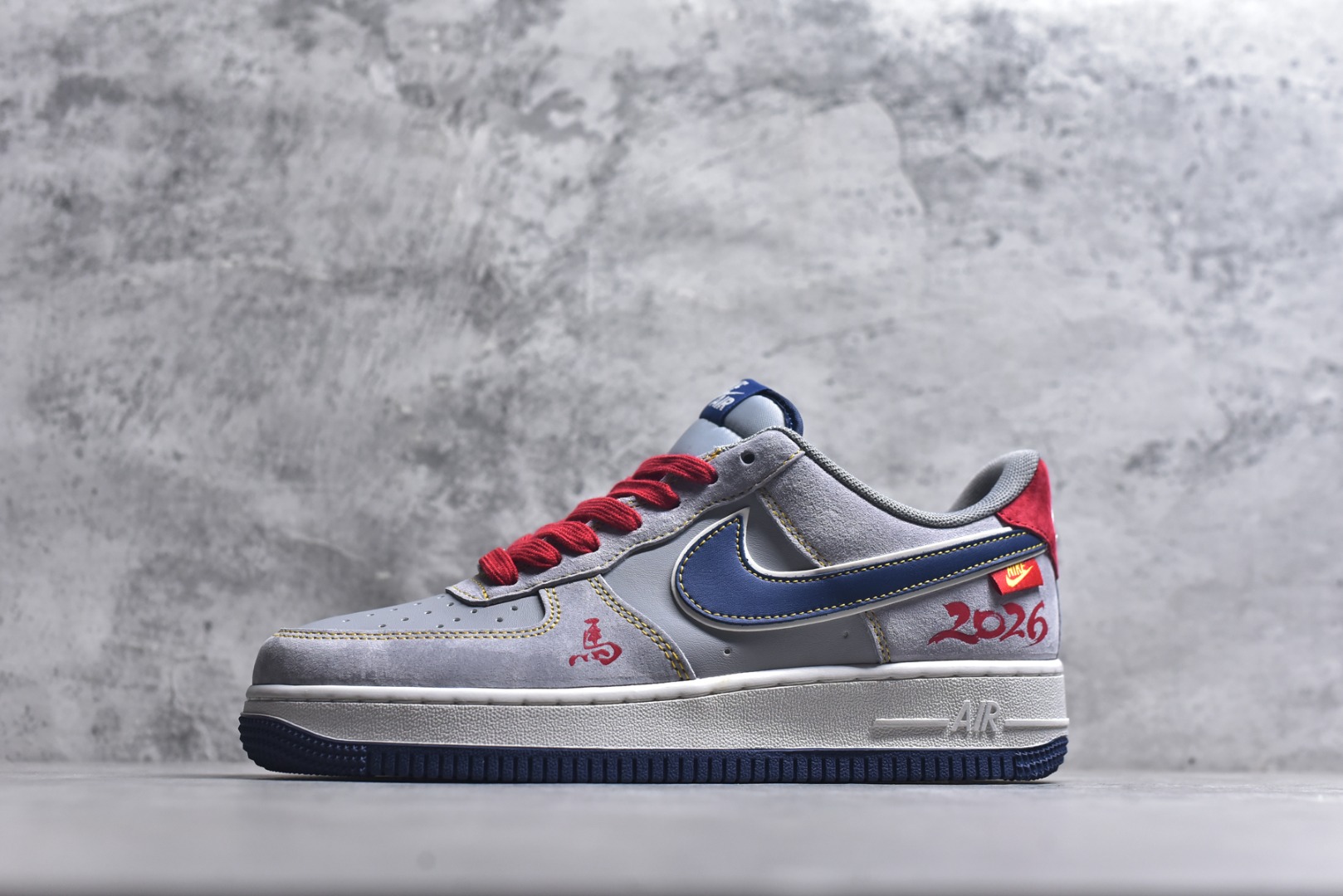 #马踏祥云 潮酷来袭AIR FORCE 1 采用灰红蓝撞色设计，麂皮材质营造复古质感，红色鞋带与鞋尾点缀点亮视觉。鞋身“马”字刺绣、2026标识搭配骏马挂饰，精准呼应马年主题，空军一号经典鞋型加持，兼具复古韵味与潮流属性。日常通勤、街头出街都适配，是马年必备的吸睛单品，轻松解锁多元风格。 货号：HT5088-623 尺码：36 36.5 37.5 38 38.5 39 40 40.5 41 42 42.5 43 44 44.5 45-选品中心