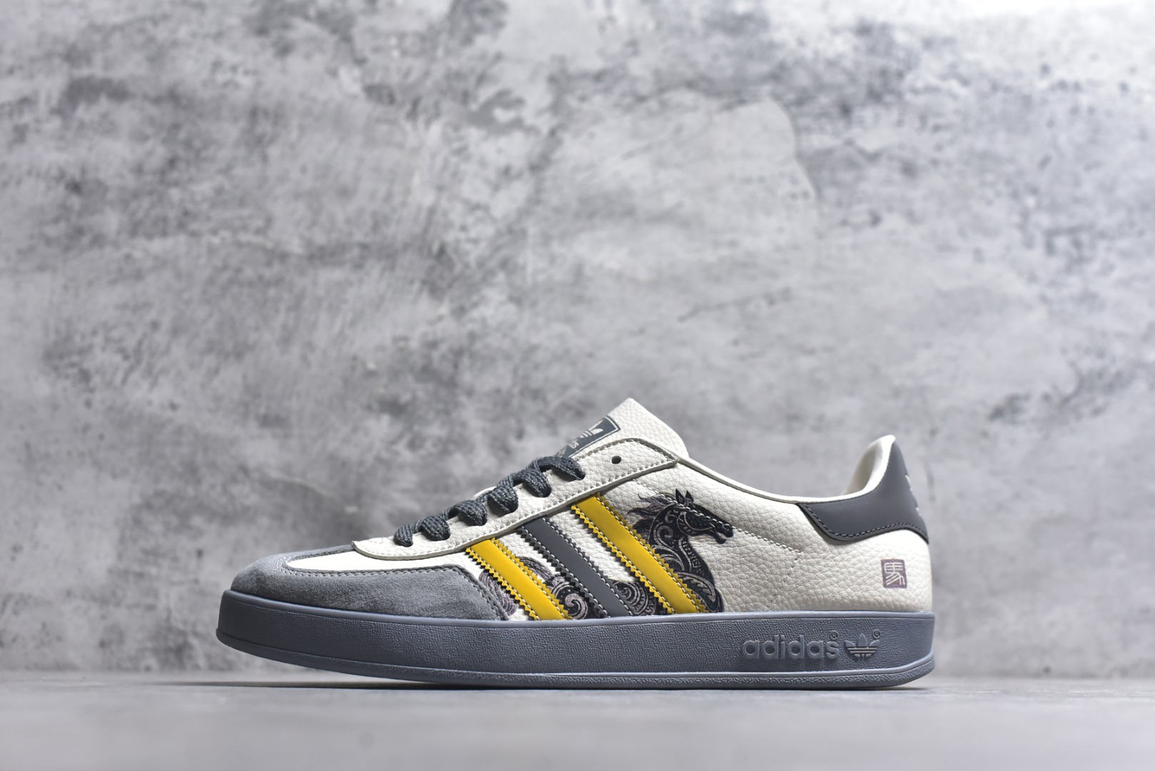 #马年新款海外定制限量发售 Adidas Originals GAZELLE INDOOR“马年联名限定-图腾腰果花”专为 2026 丙午马年打造的限定德训鞋，延续 adidas 经典板鞋版型，软弹中底兼顾支撑性与舒适度，经典三道杠升级为黄黑撞色，在米白帆布与灰色翻毛皮的基底上更具视觉冲击力，鞋身侧部的骏马纹样线条细腻，绒面鞋面柔软亲肤，橡胶防滑大底稳当贴脚 货号：JJ2605 尺码：36 36.5 37.5 38 38.5 39 40 40.5 41 42 42.5 43 44 44.5 45-选品中心