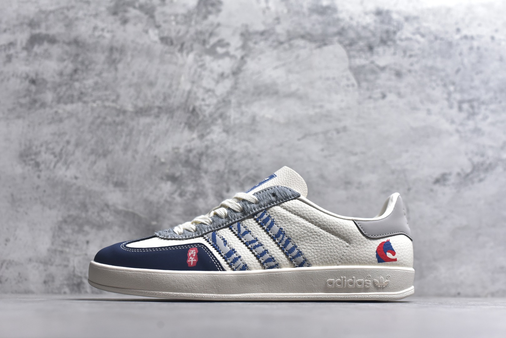 #马年新款海外定制限量发售 Adidas Originals GAZELLE INDOOR“马年联名限定-蓝白”专为 2026 丙午马年打造的限定德训鞋，延续 adidas 经典板鞋版型，软弹中底兼顾支撑性与舒适度，鞋头的丙午印章与鞋侧的骏马剪影，点明 2026 马年专属身份，经典三道杠升级为蓝白民族风提花织带，绒面鞋面柔软亲肤，橡胶防滑大底稳当贴脚 货号：JJ2603 尺码：36 36.5 37.5 38 38.5 39 40 40.5 41 42 42.5 43 44 44.5 45-选品中心