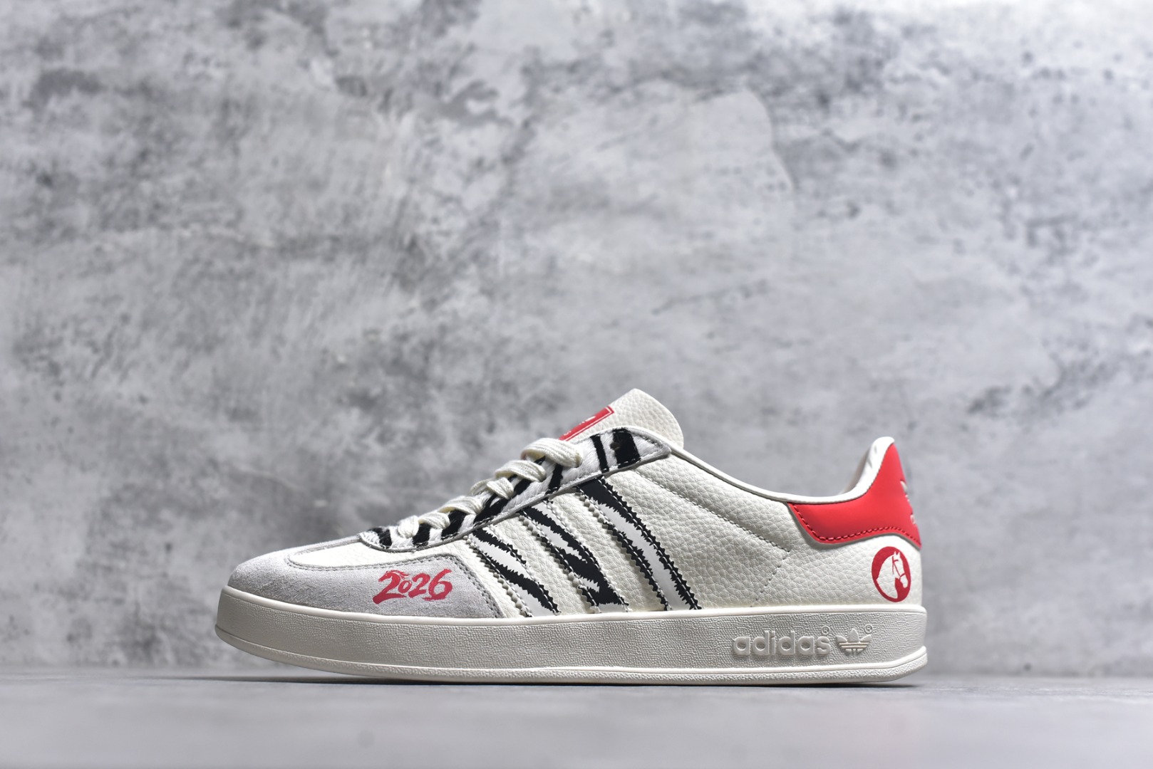 #马年新款海外定制限量发售 Adidas Originals GAZELLE INDOOR“马年联名限定-白红虎纹”专为 2026 丙午马年打造的限定德训鞋，延续 adidas 经典板鞋版型，经典三道杠采用黑白虎纹织带设计，纹理呈现自然的笔触质感，鞋尾搭配正红鞋跟与圆形骏马印章刺绣，红黑白三色碰撞，打破纯色条纹的单调，荔枝皮鞋面柔软亲肤，橡胶防滑大底稳当贴脚 货号：JJ2601 尺码：36 36.5 37.5 38 38.5 39 40 40.5 41 42 42.5 43 44 44.5 45-选品中心