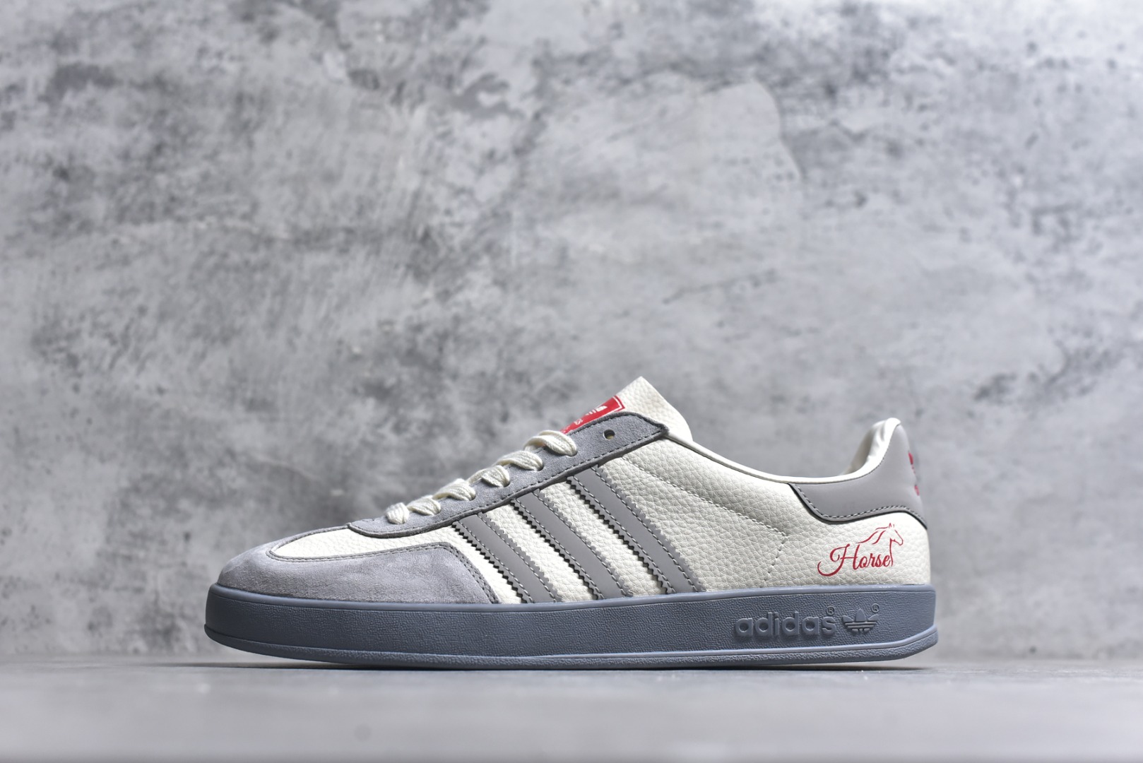 #马年新款海外定制限量发售 Adidas Originals GAZELLE INDOOR“马年联名限定-浅灰红马”专为 2026 丙午马年打造的限定德训鞋，延续 adidas 经典板鞋版型，鞋尾印有红色手写体Horse字样与骏马剪影，笔触轻盈醒目，鞋身主体为米白荔枝纹皮革，搭配浅灰磨砂皮鞋头、同色系三道杠及雾灰橡胶外底，荔枝皮鞋面柔软亲肤，橡胶防滑大底稳当贴脚 货号：ZH2598 尺码：36 36.5 37.5 38 38.5 39 40 40.5 41 42 42.5 43 44 44.5 45-选品中心
