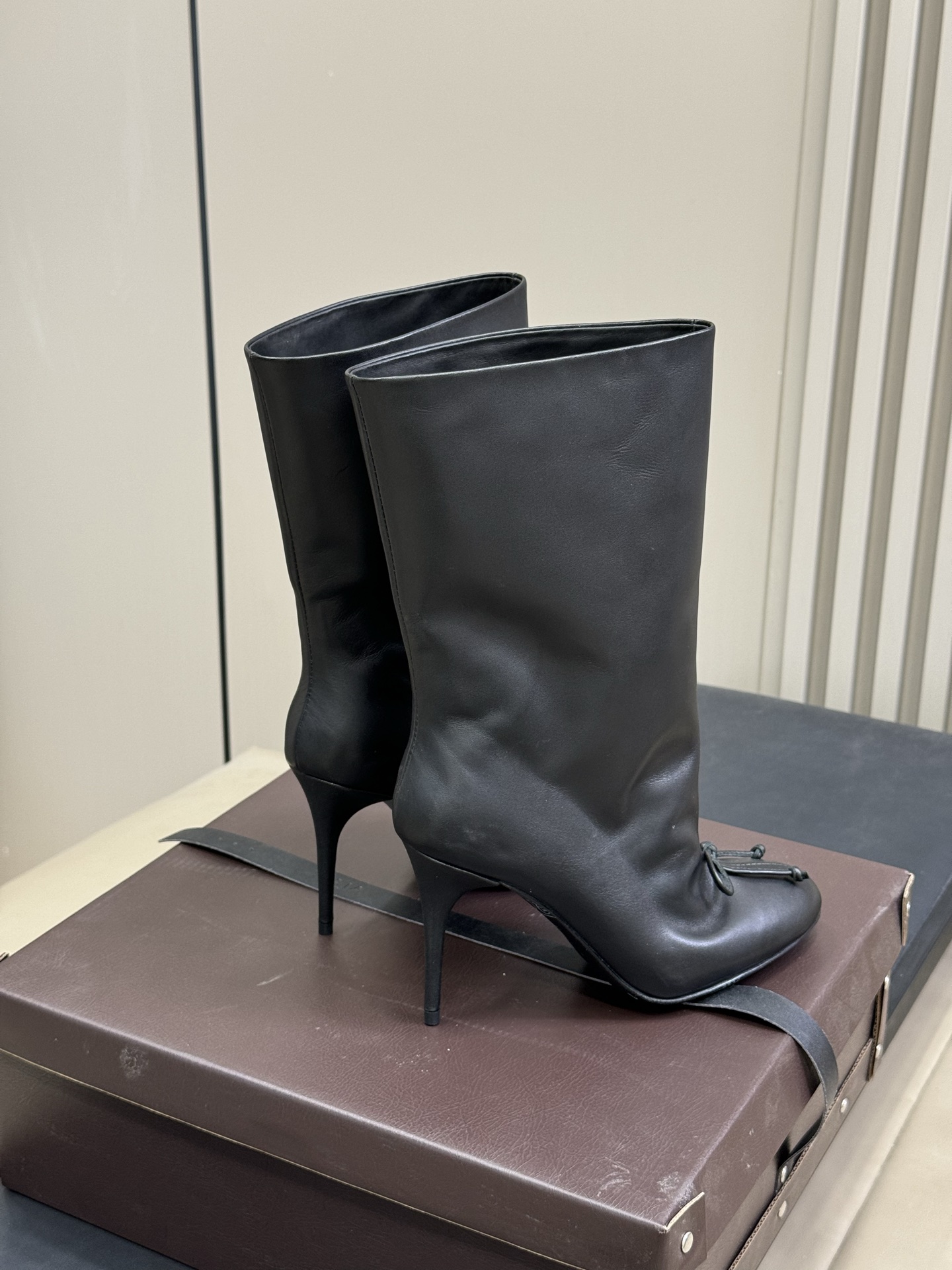 
ALAIA｜易梦玲同款高跟短靴
该款黑色小牛皮高跟短靴，正面点缀装饰蝴蝶结，搭配90毫米鞋跟与22厘米