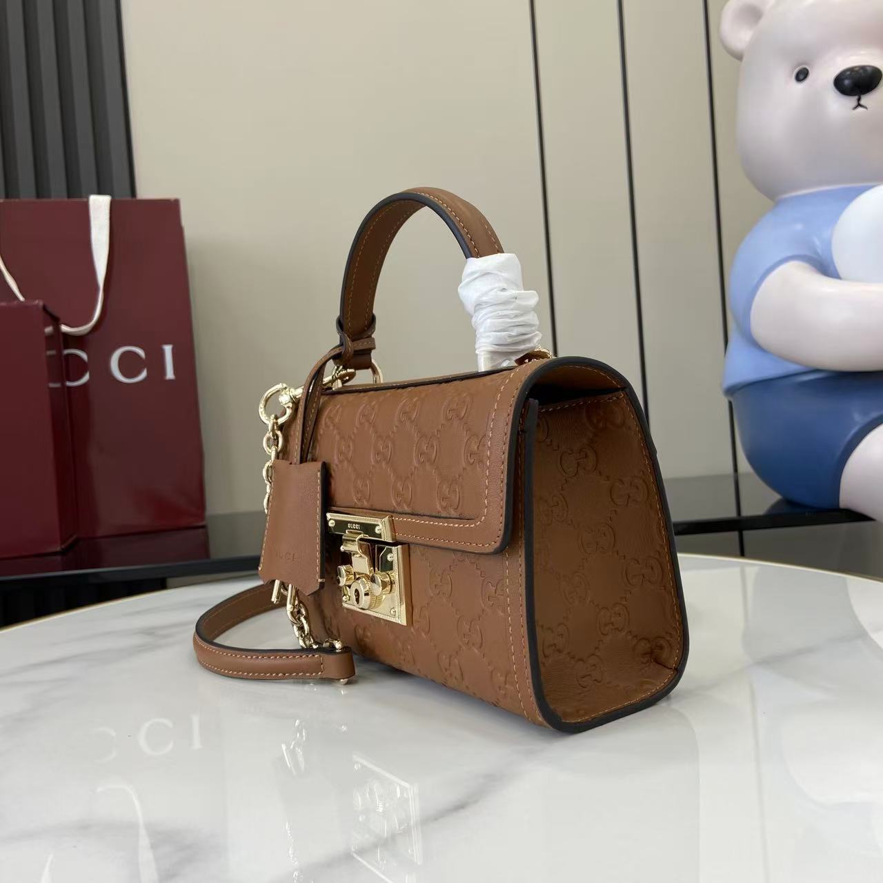 p640。《配全套原厂专柜包装》【新品】Padlock系列以现代廓形惊艳亮相2025早秋系列，解锁多种背携方式。此款式手提或斜挎皆宜，织带衬里致敬品牌标志性元素。
棕色GG字母交织图案涂层织物
棕色皮革滚边
浅金色调配件
棕色棉布衬里
内部：一个开口袋
外部：一个开口袋
提手（6厘米高）
可拆卸可调节皮革肩带（高度：57厘米 – 62厘米；长度：103厘米 – 123厘米）
挂锁锁扣，配有皮革钥匙扣
型号：848884。
尺寸：20厘米（宽）x 13厘米（高）x 8厘米（深）
重量：约0.6千克
颜色：棕色/压花。
意大利创作