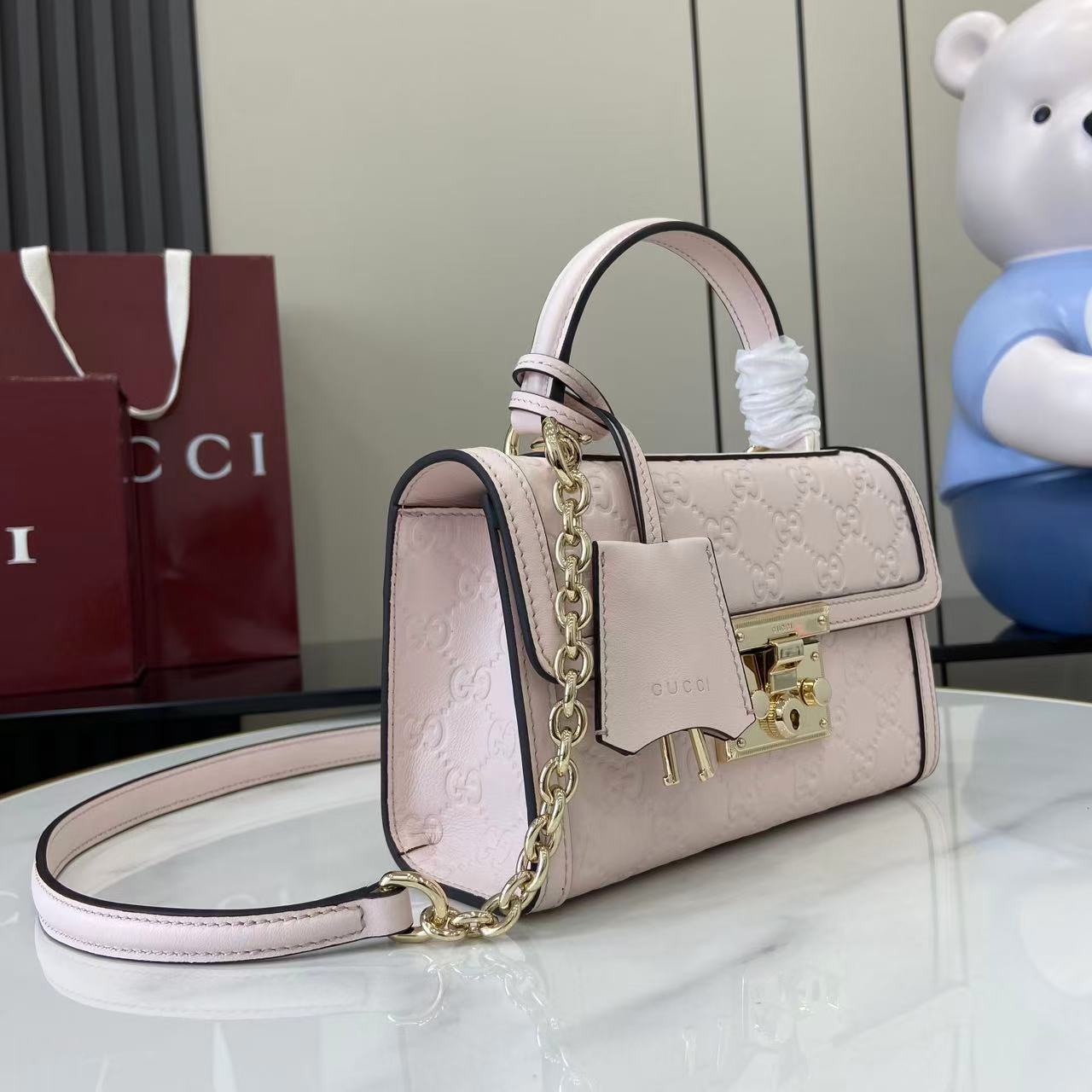 p640。《配全套原厂专柜包装》【新品】Padlock系列以现代廓形惊艳亮相2025早秋系列，解锁多种背携方式。此款式手提或斜挎皆宜，织带衬里致敬品牌标志性元素。
浅粉色GG字母交织图案涂层织物
浅粉色皮革滚边
浅金色调配件
浅粉色棉布衬里
内部：一个开口袋
外部：一个开口袋
提手（6厘米高）
可拆卸可调节皮革肩带（高度：57厘米 – 62厘米；长度：103厘米 – 123厘米）
挂锁锁扣，配有皮革钥匙扣
型号：848884。
尺寸：20厘米（宽）x 13厘米（高）x 8厘米（深）
重量：约0.6千克
颜色：浅粉色/压花。
意大利创作